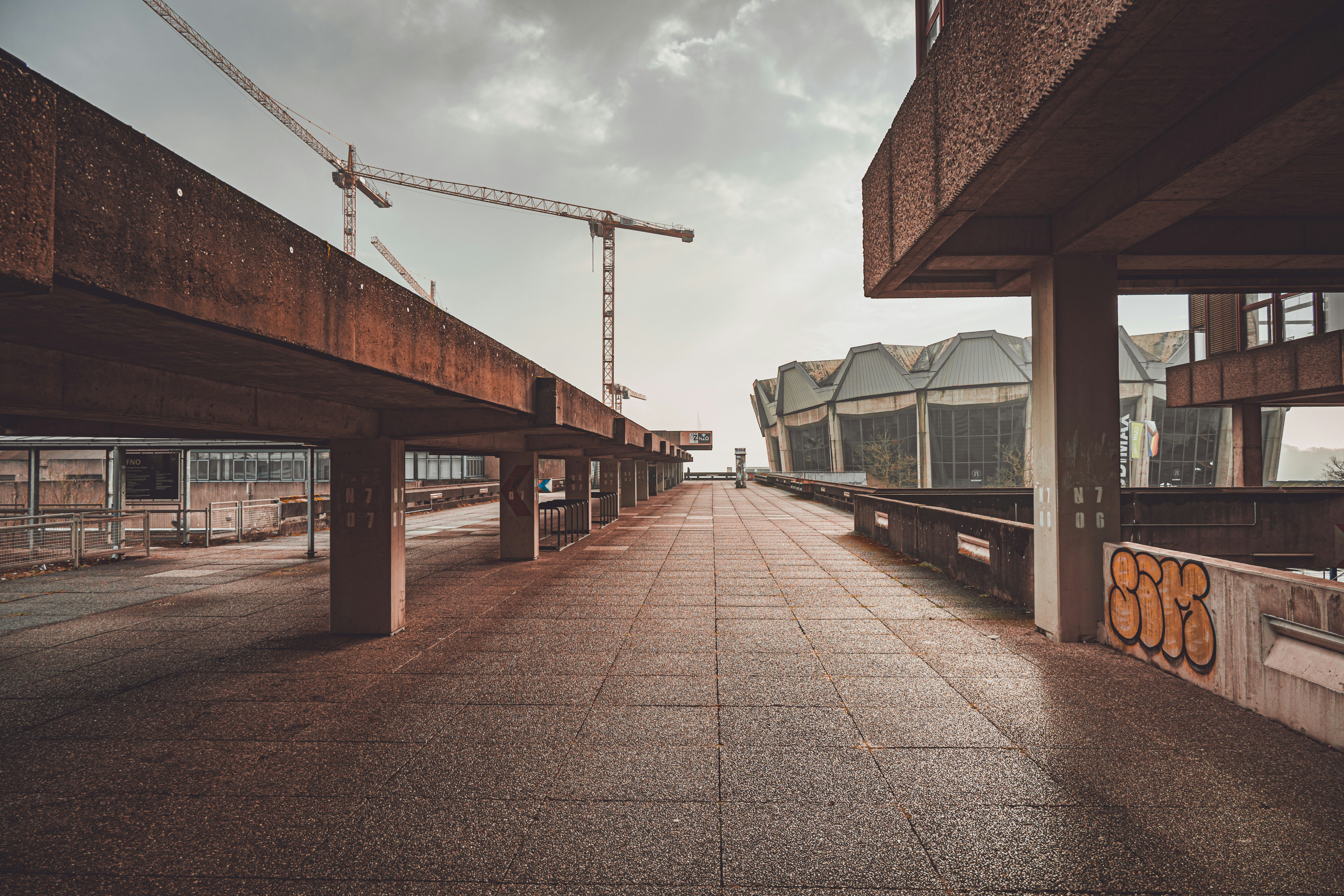 Abandoned industrial walkway with cranes in background