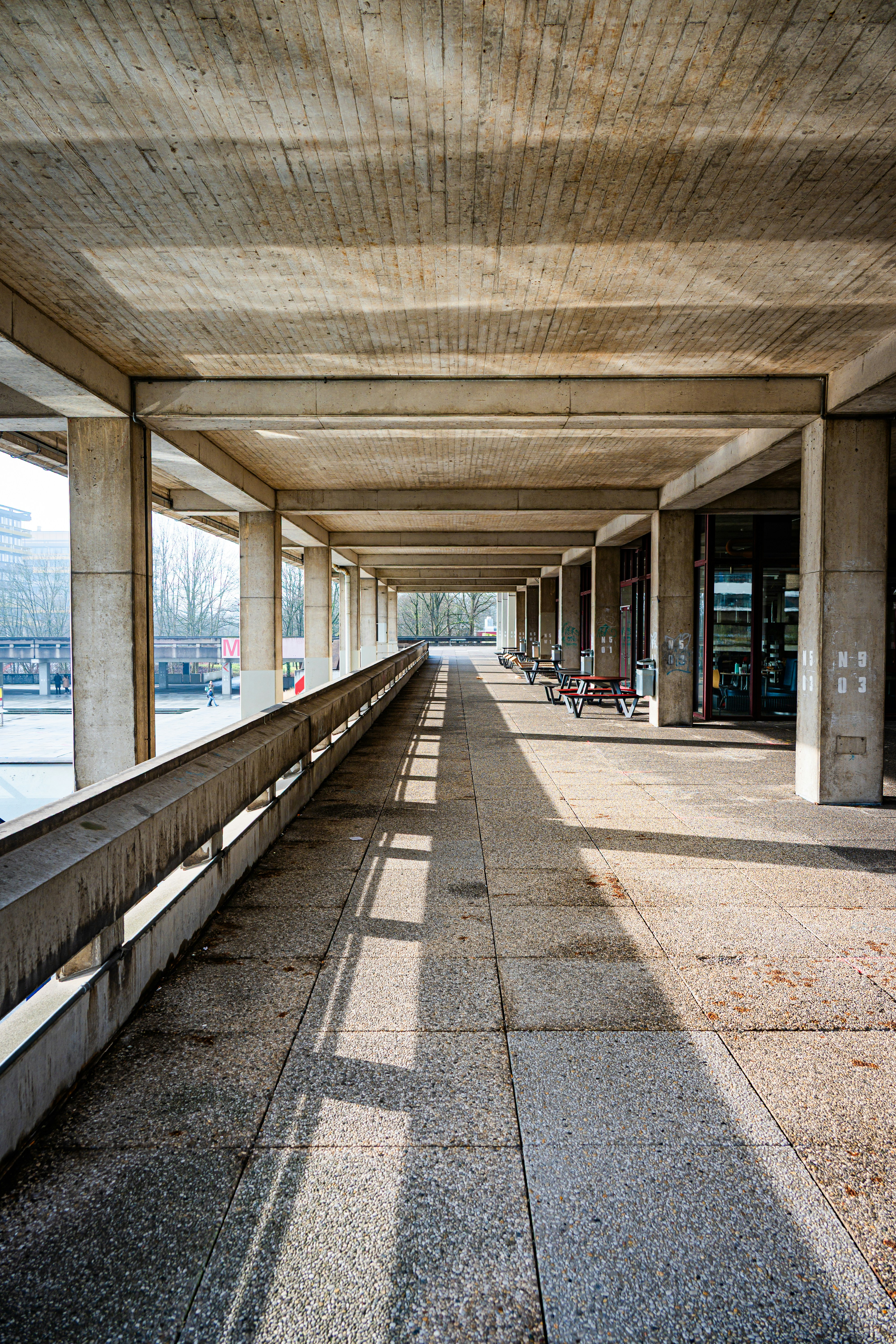 Long concrete walkway with columns and sunlight patterns