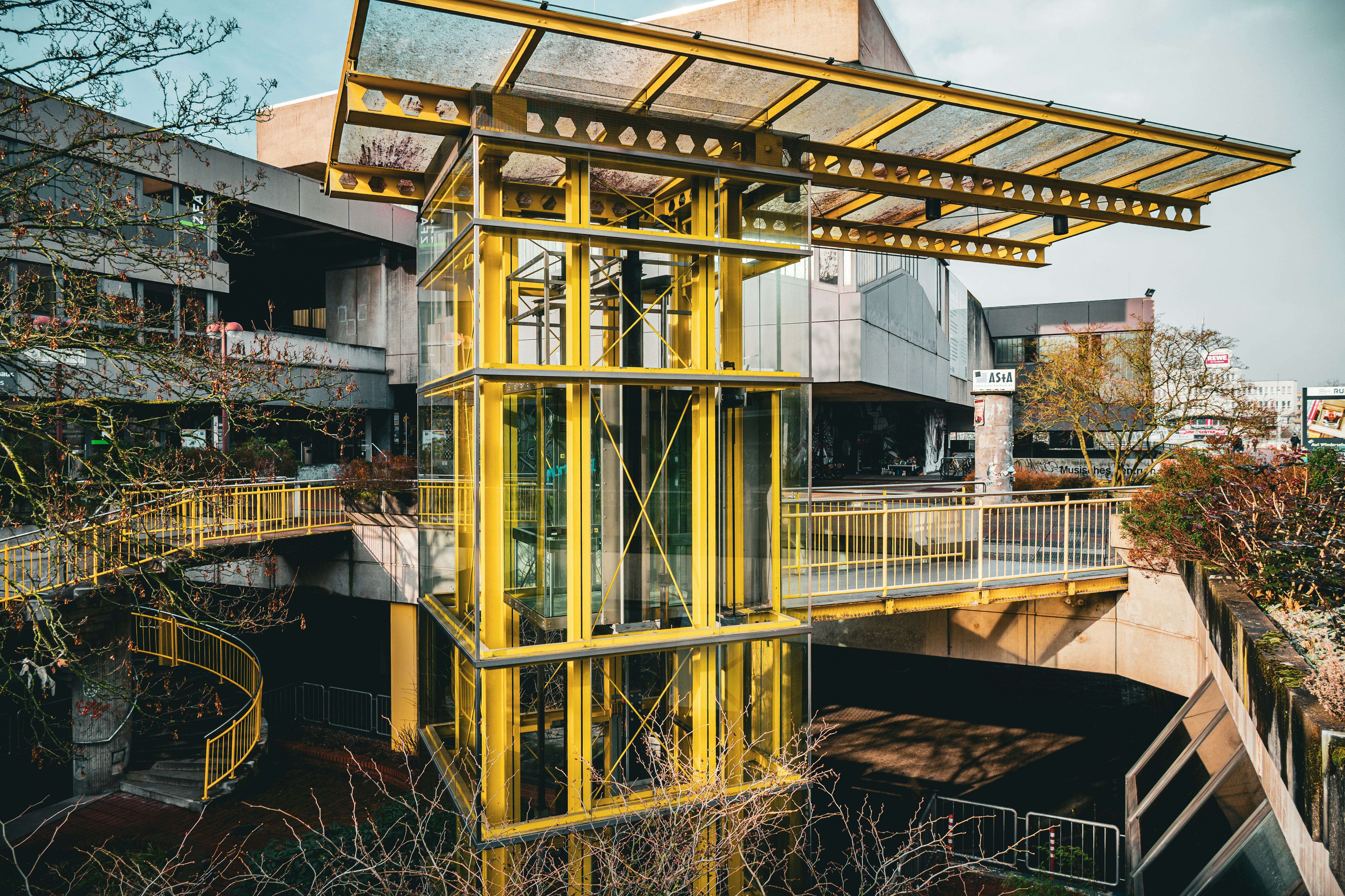 Modern yellow structure with surrounding buildings and greenery