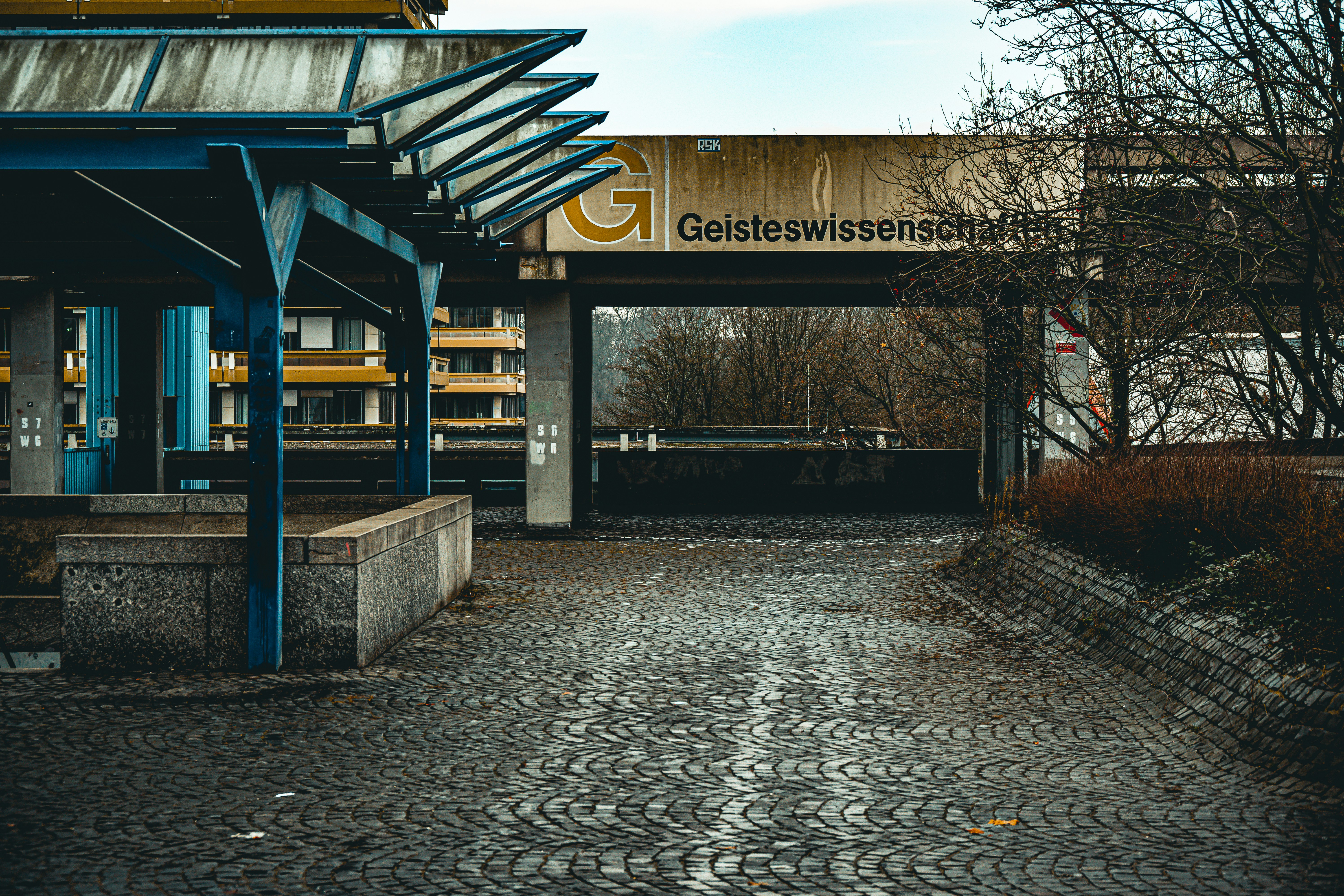 Modern building entrance with cobblestone path and signage.