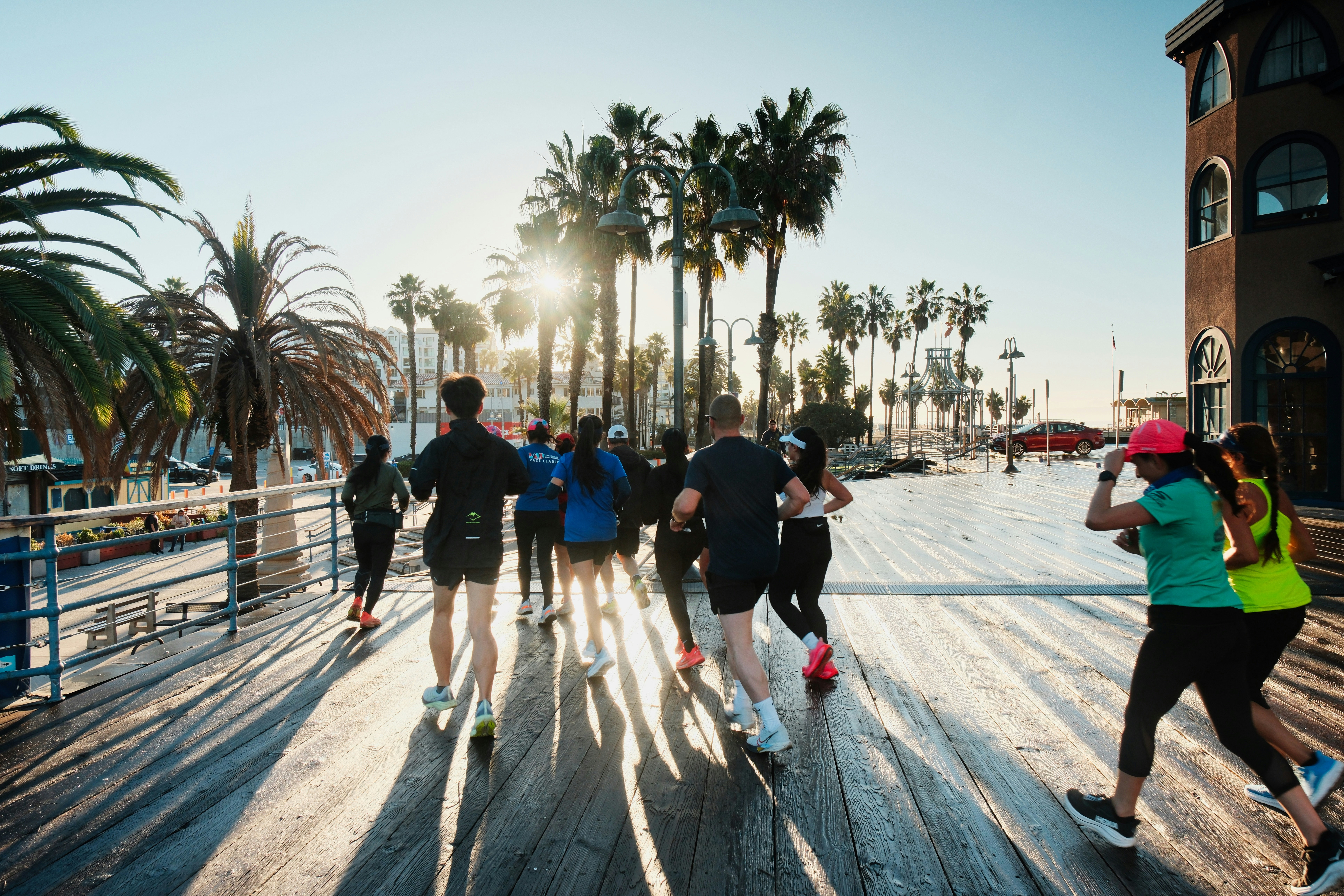 Group of runners on a boardwalk with palm trees.