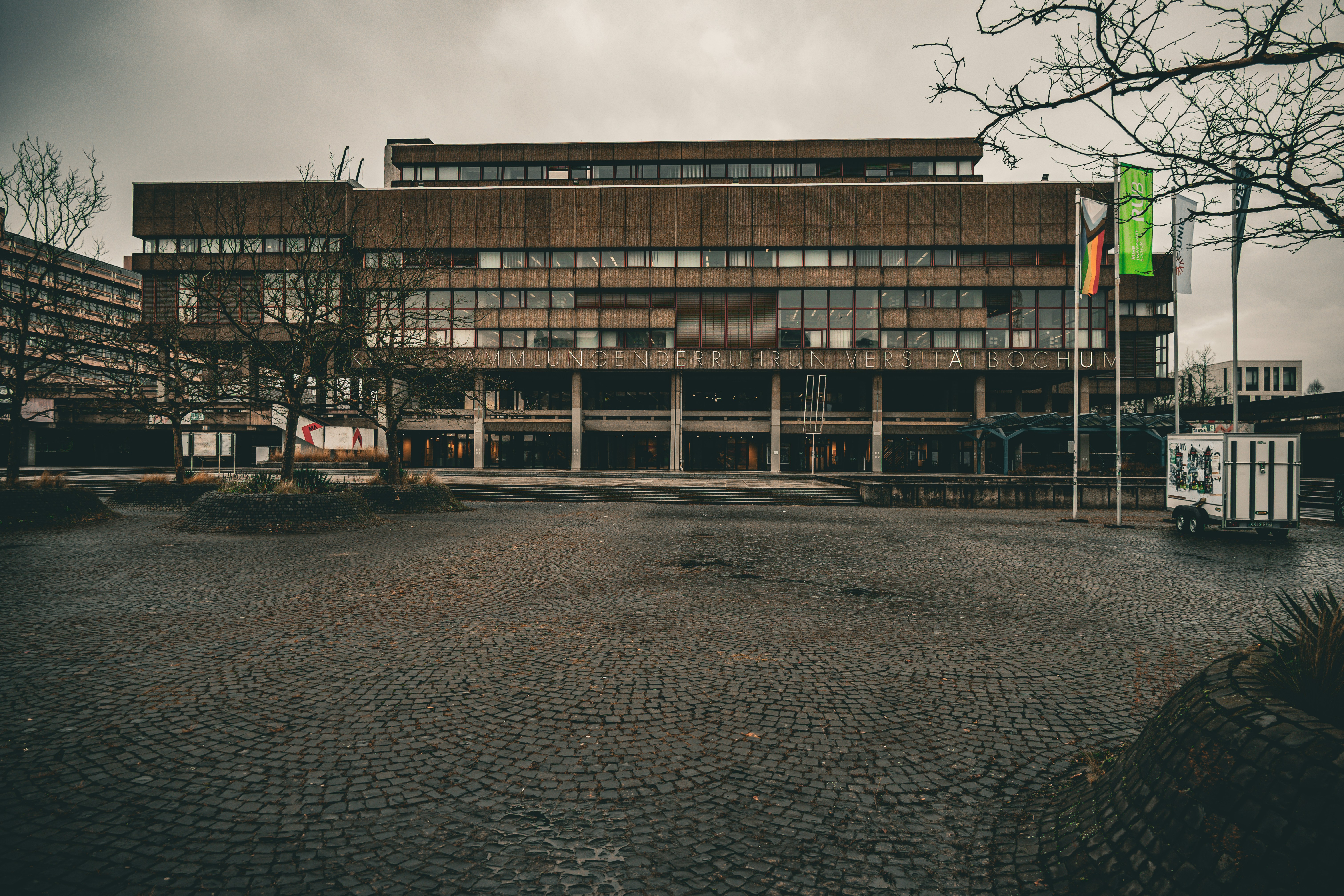A modern building with glass windows and flags