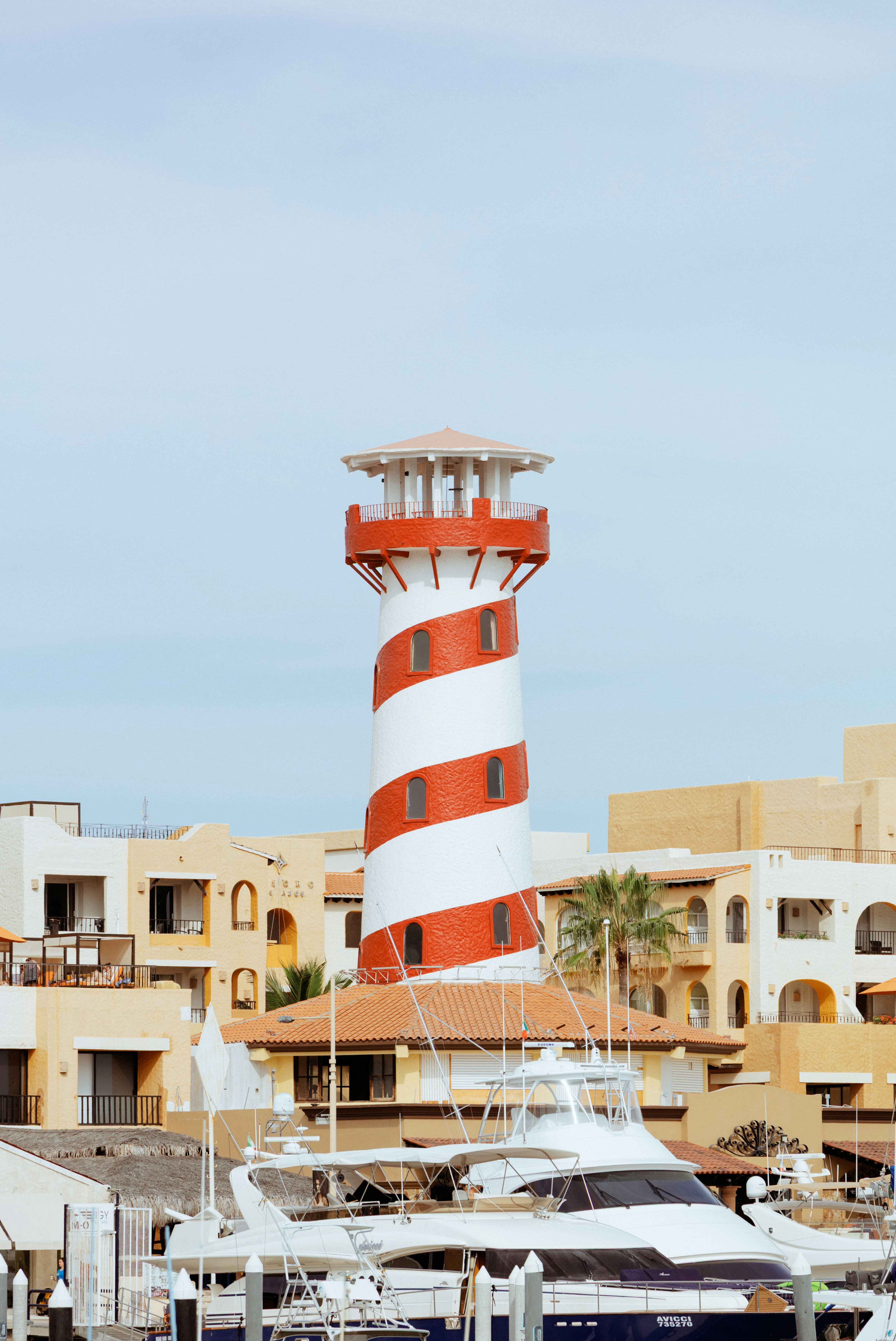 Rot-weiß gestreifter Leuchtturm mit Booten und Gebäuden