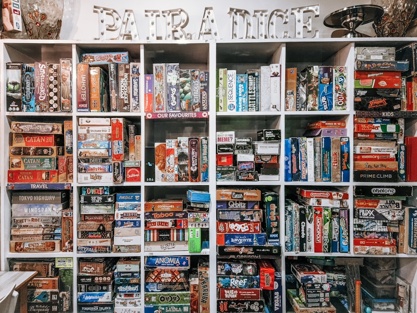 Organized shelves displaying a curated collection of colourful board game boxes arranged by category