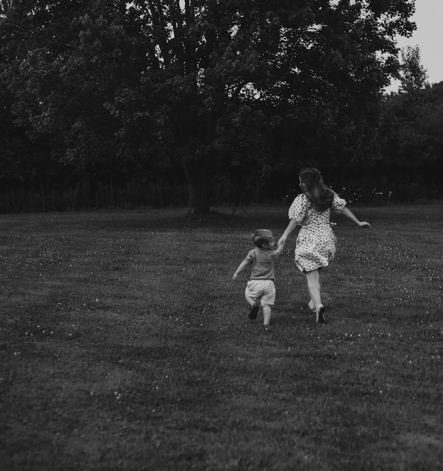 Two children running hand-in-hand across a grassy field