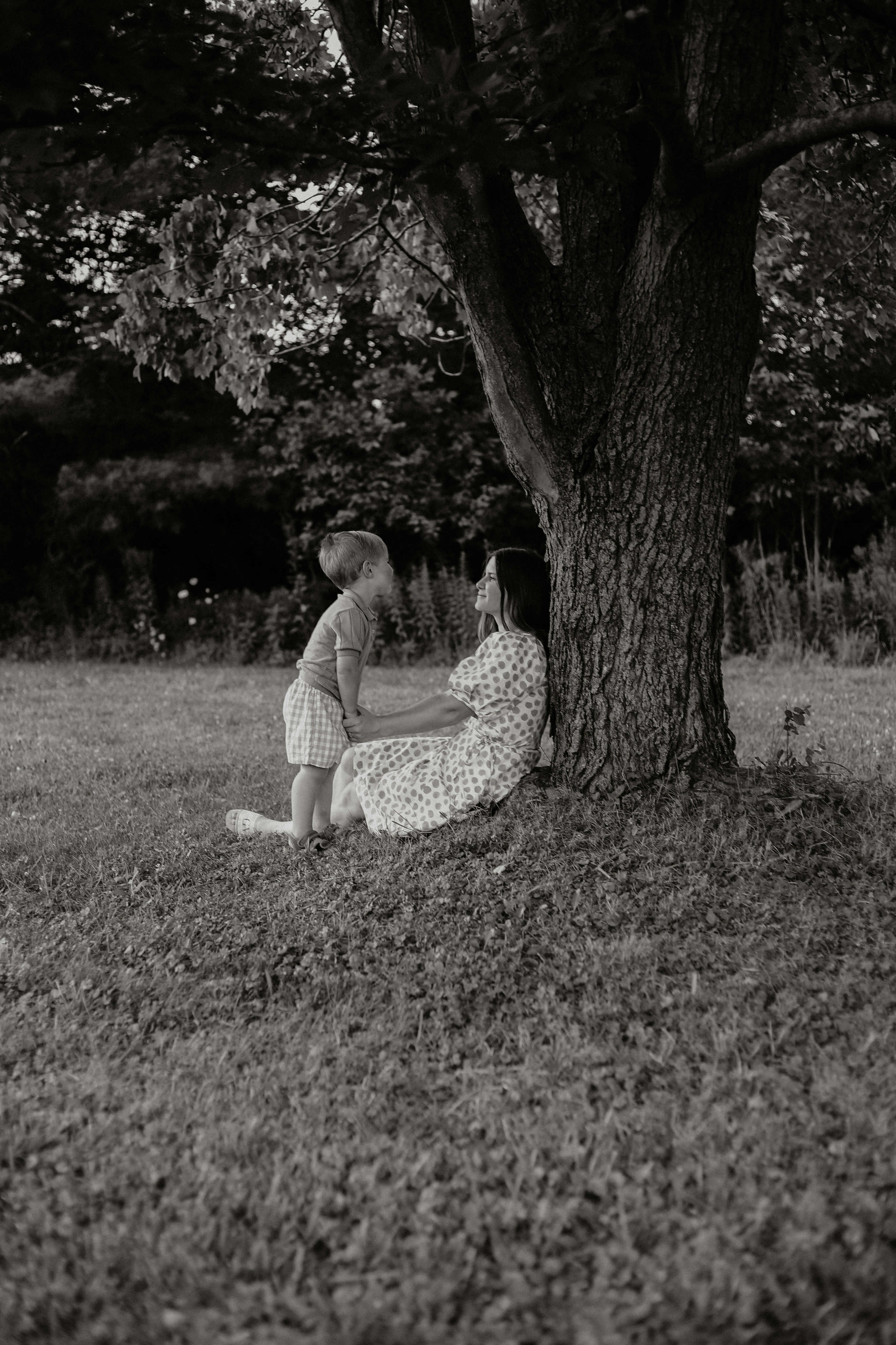 Mother and child resting under a large tree