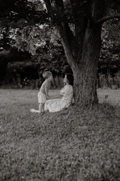 Mother and child resting under a large tree