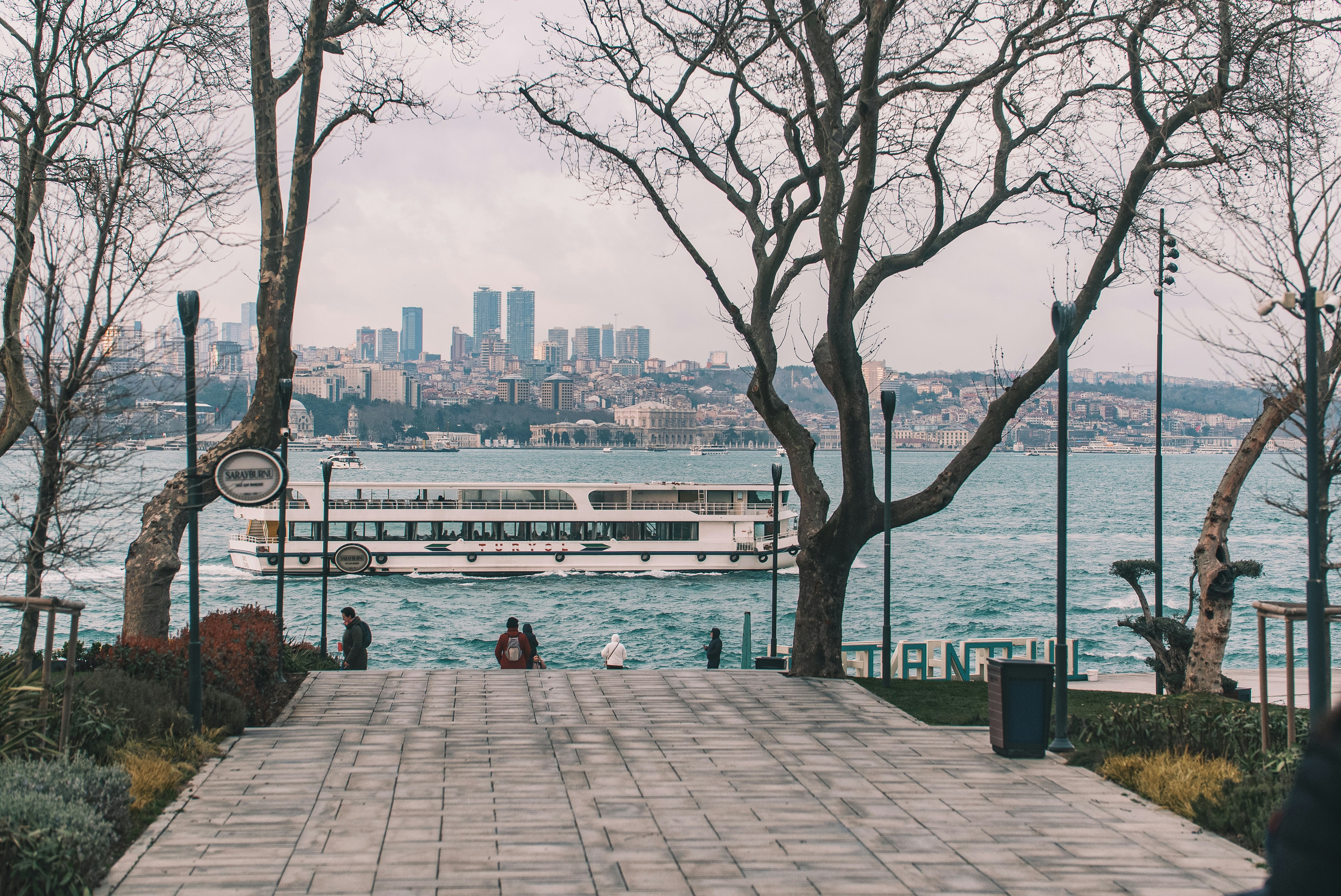 A ferry sails on the water with a city skyline.