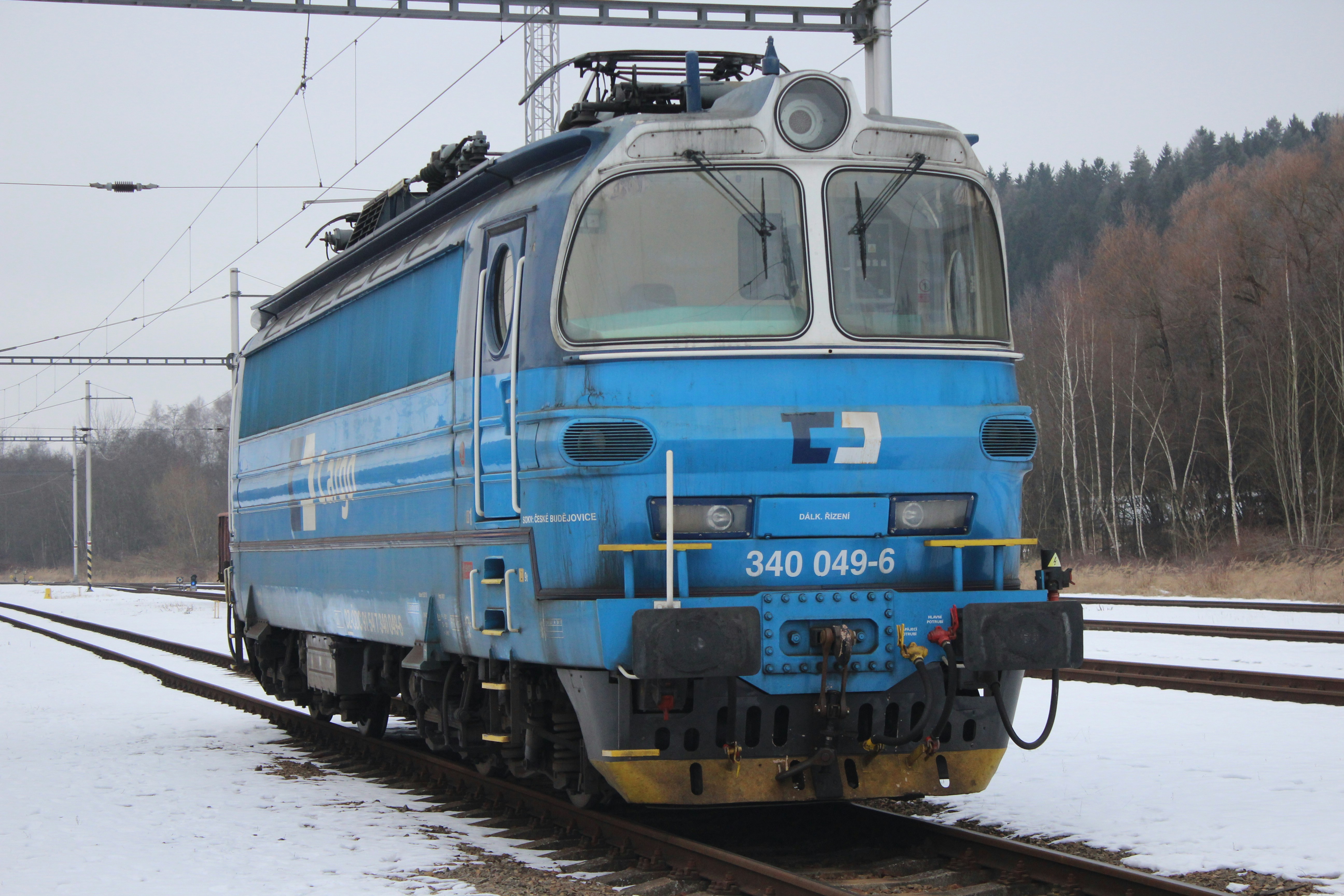 Blue electric locomotive on snowy train tracks.