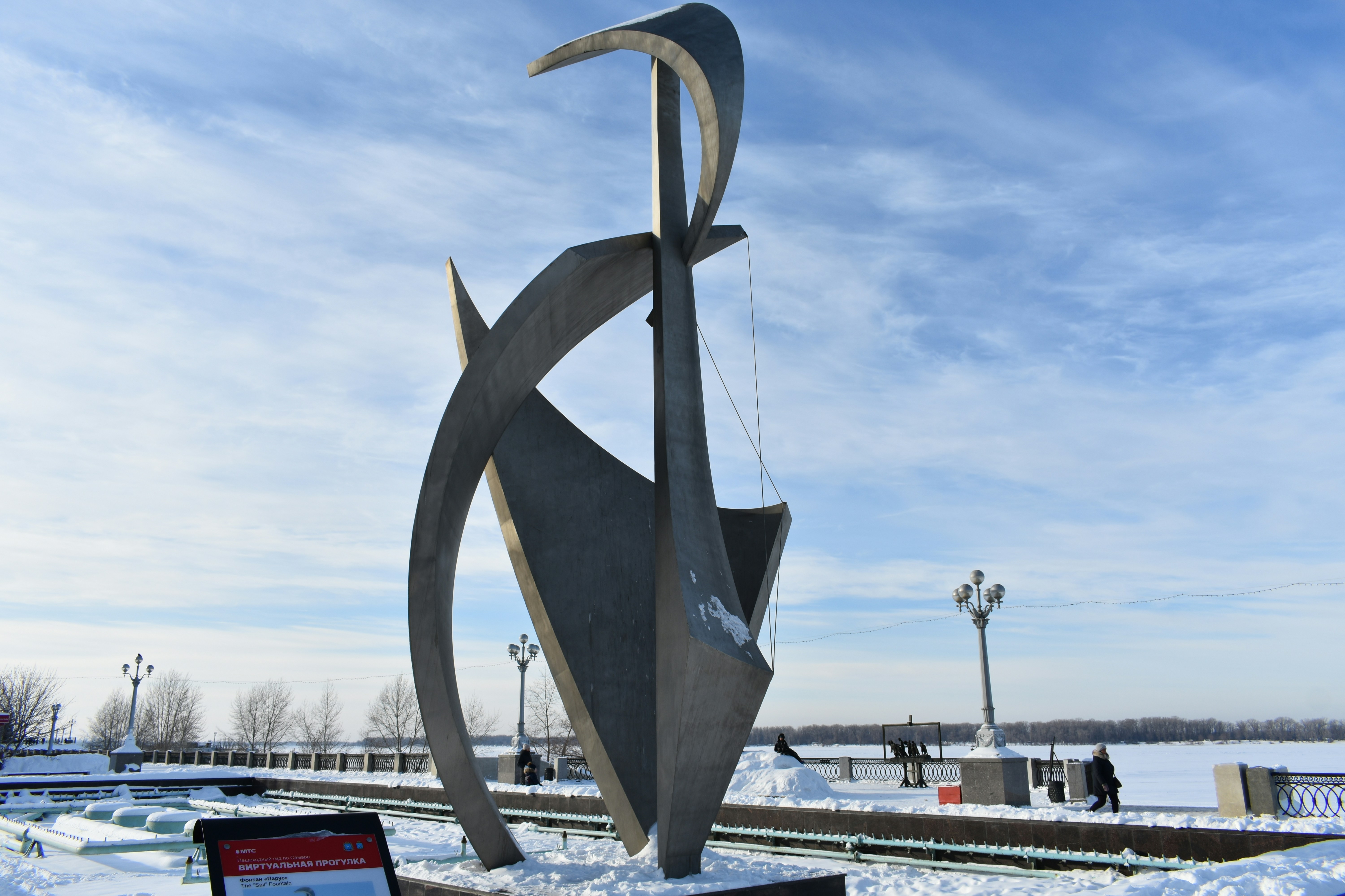 Modern metal sculpture in a snowy park setting.