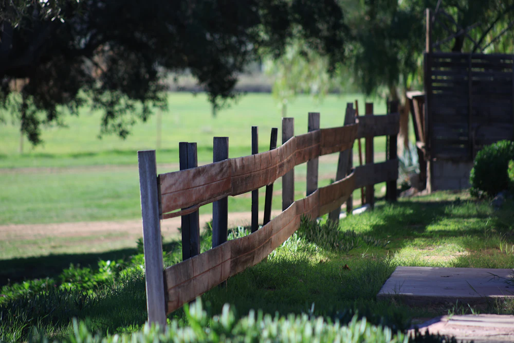 Wooden post-and-rail fence across a shady green pasture