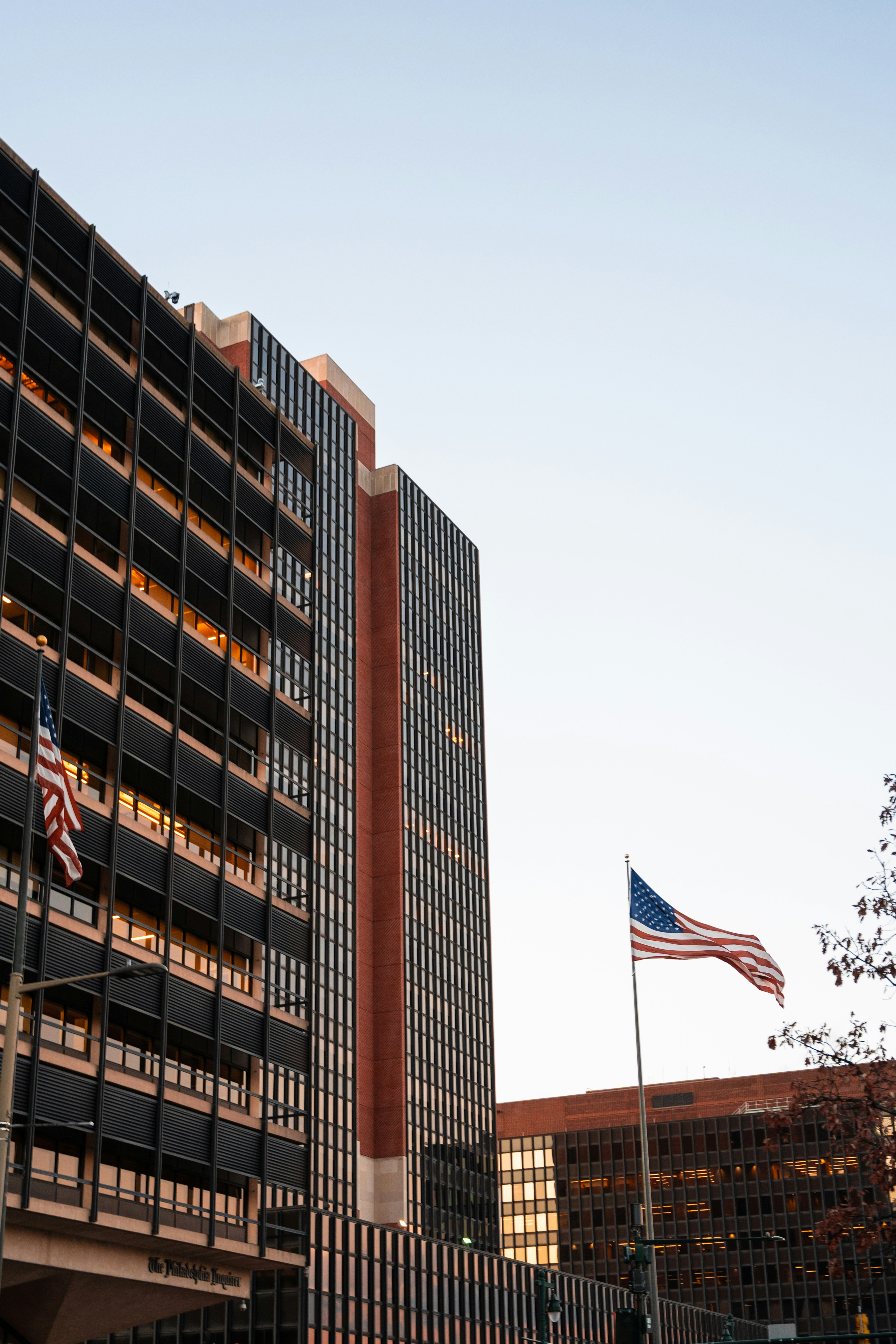 American flags fly near modern buildings under a clear sky.