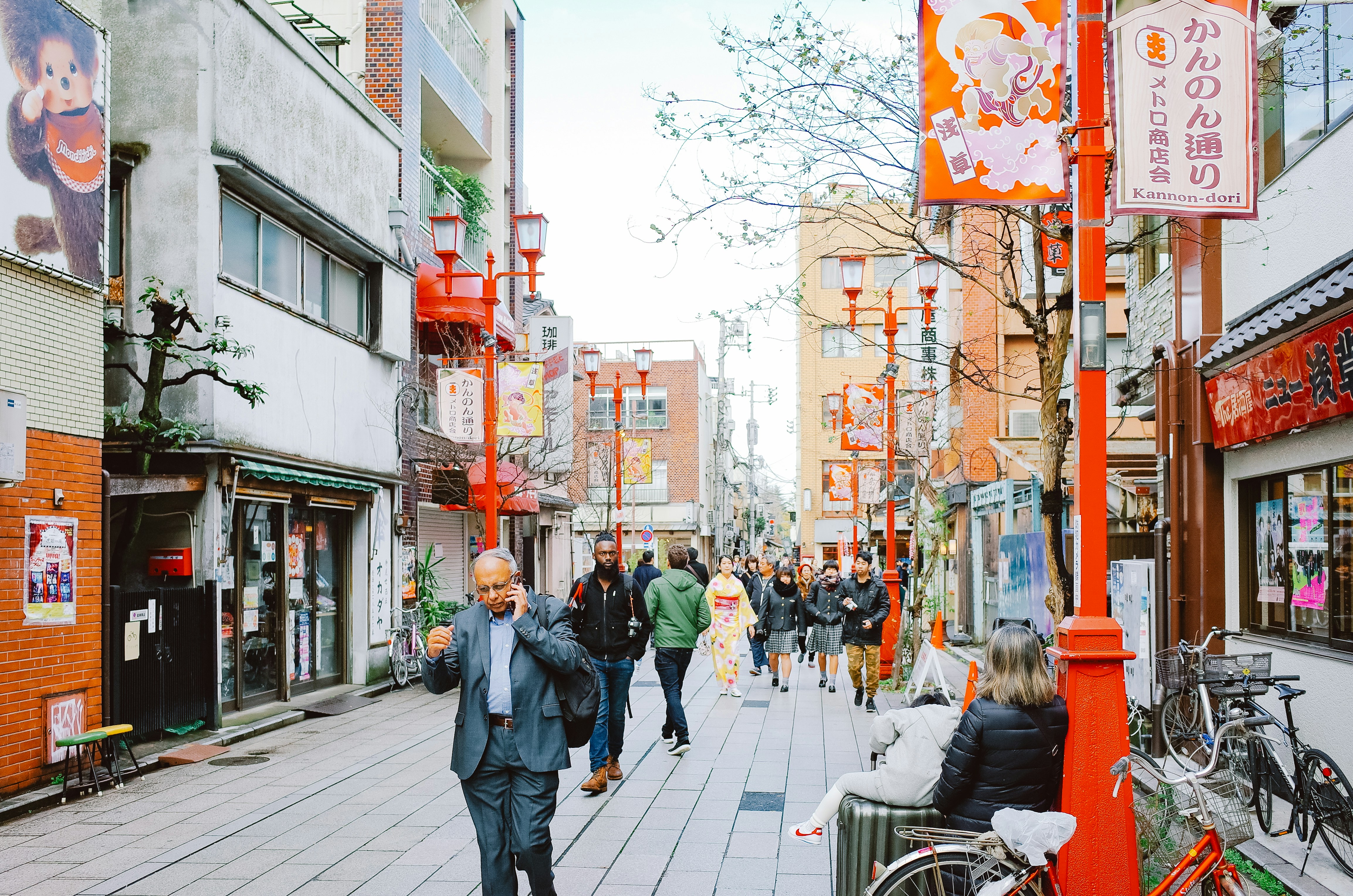 People walking down a narrow street with shops and signs.
