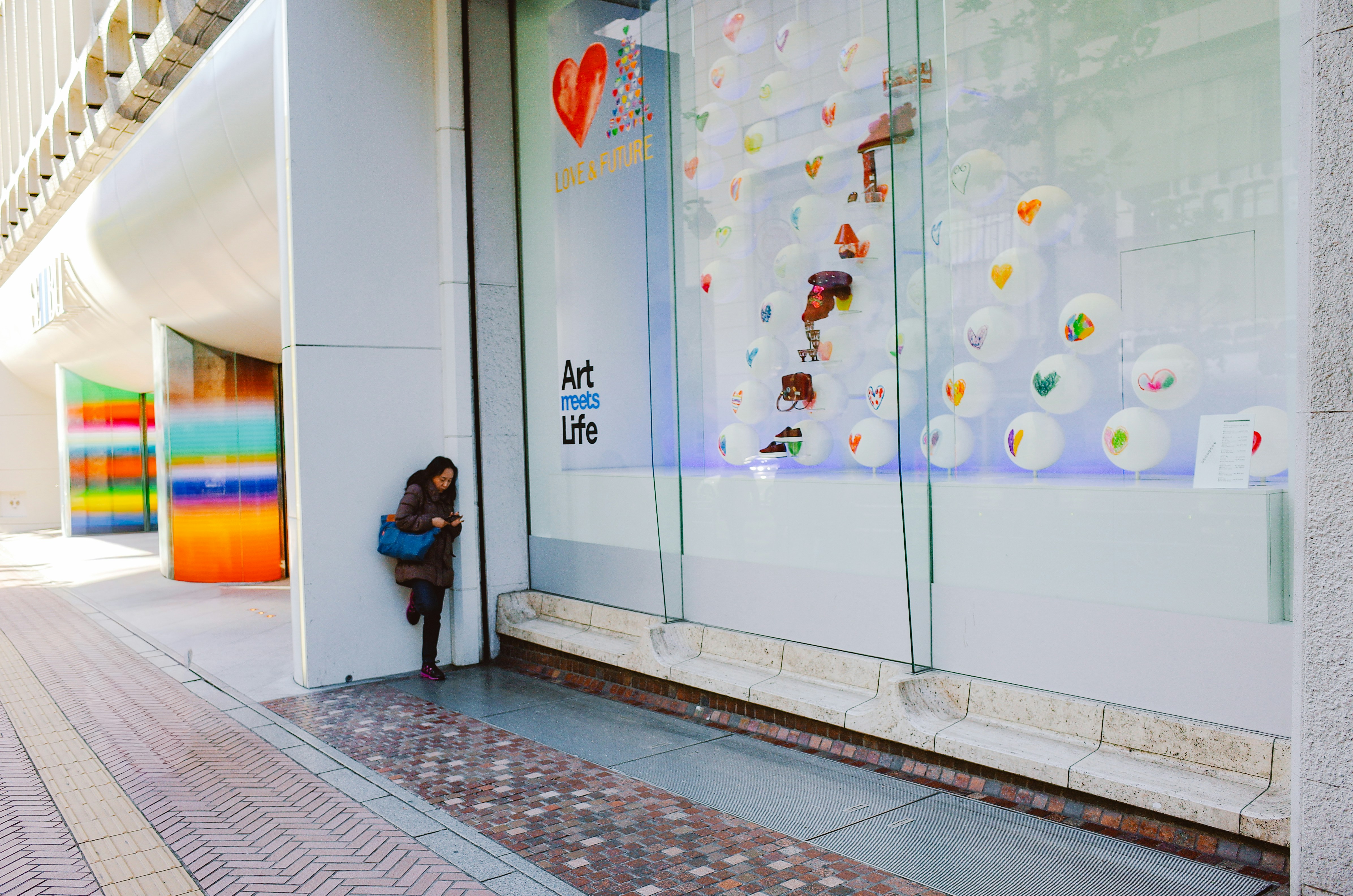 Woman leaning against building near store window
