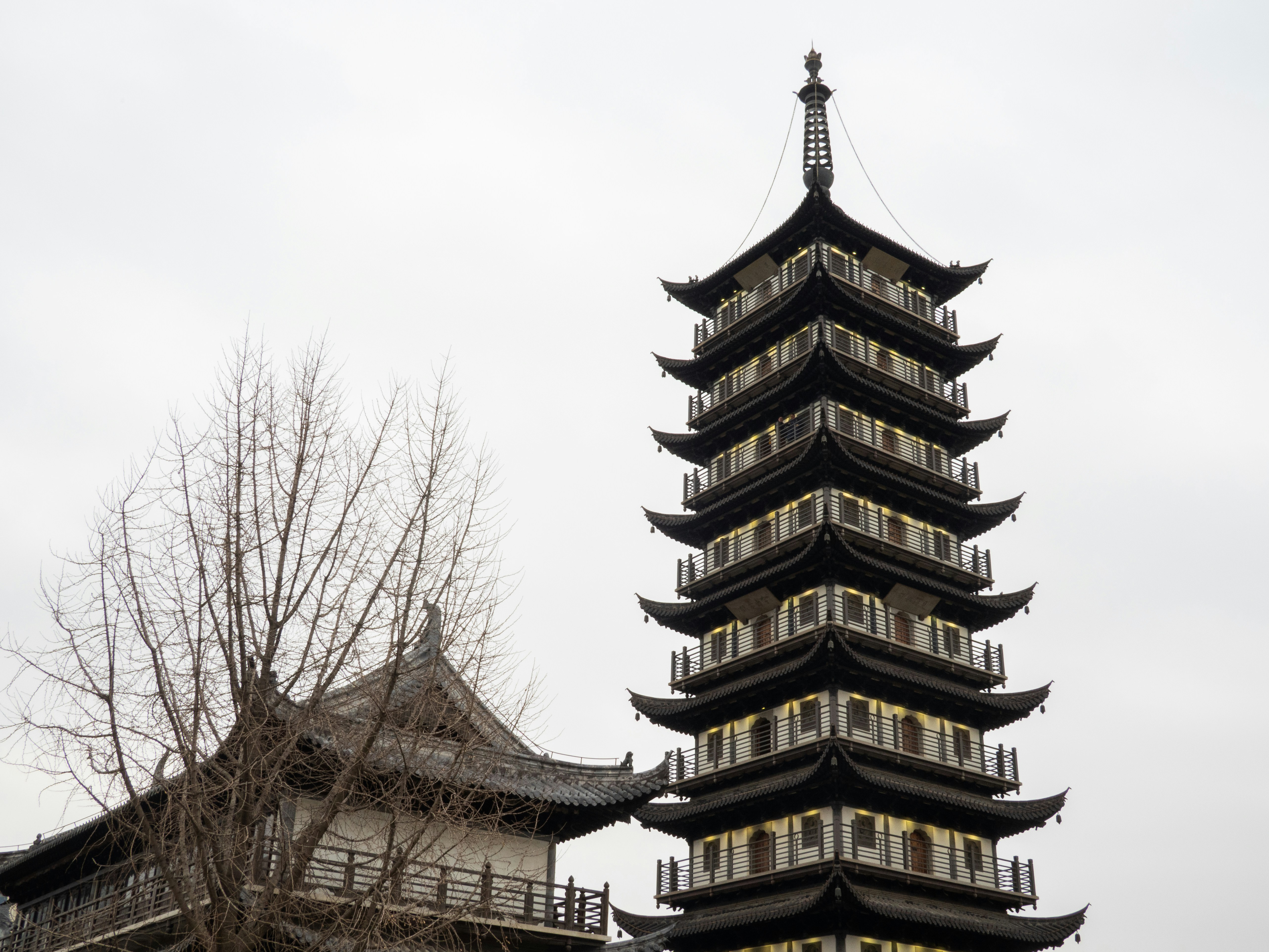 A tall, multi-tiered pagoda stands against a cloudy sky.