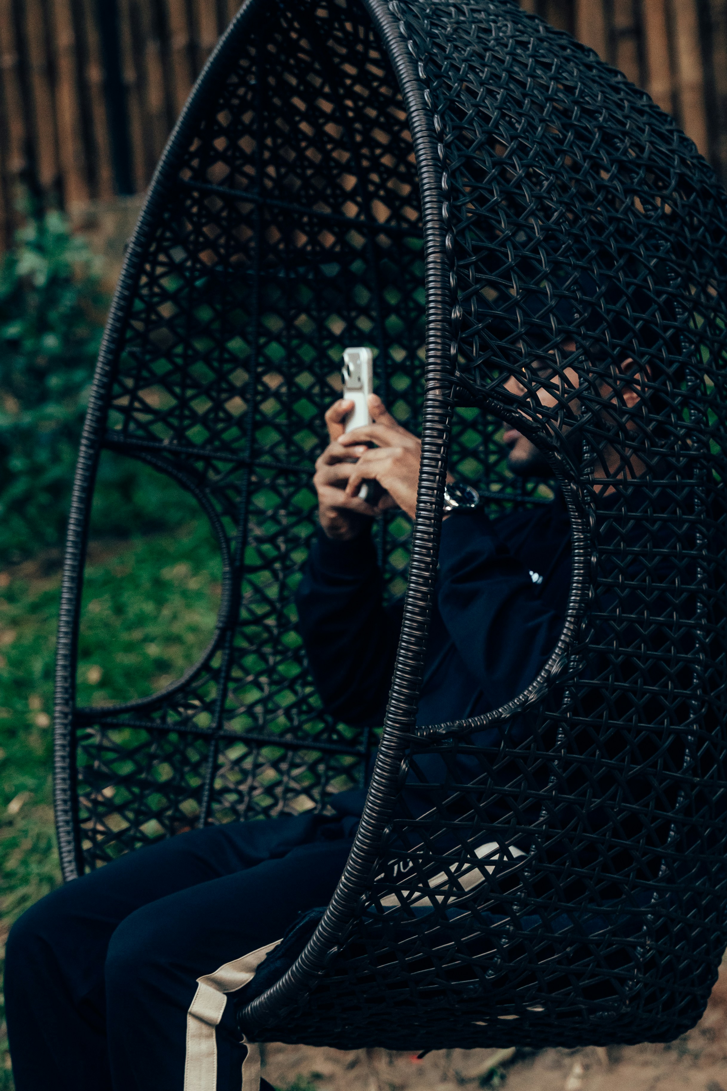 Man sitting in a hanging chair looking at phone