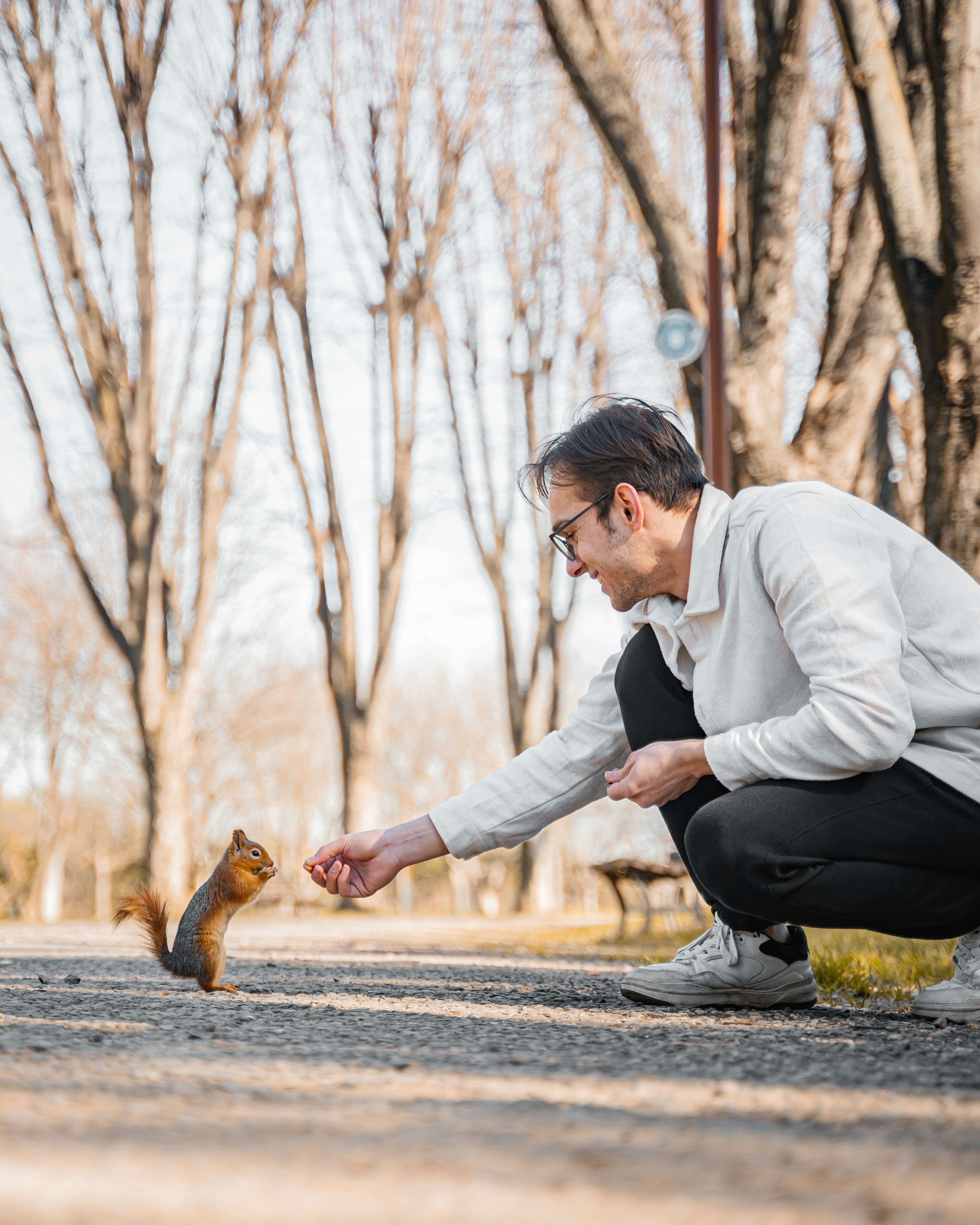 Man feeding a squirrel in a park.