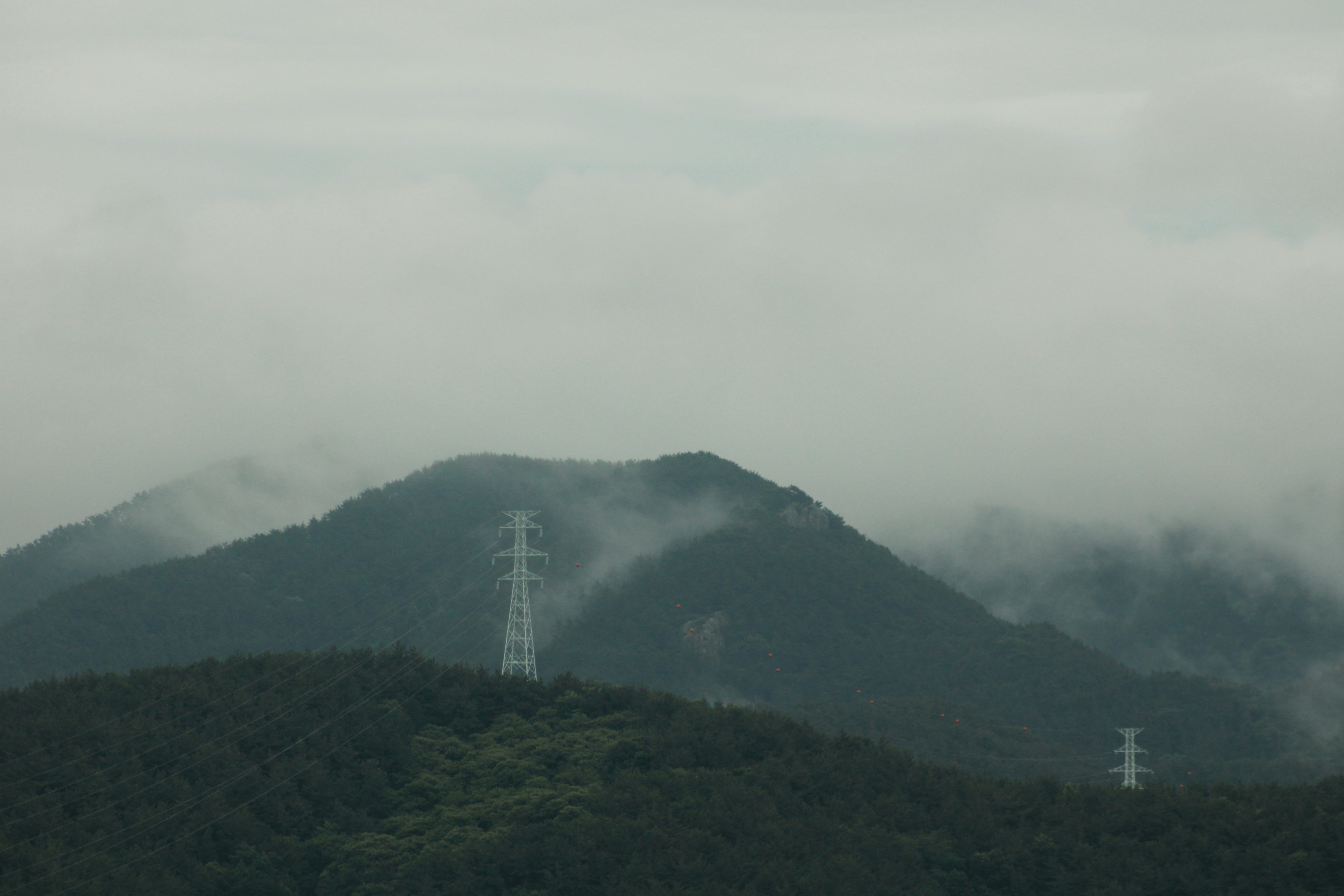 Misty mountains with power lines on a cloudy day