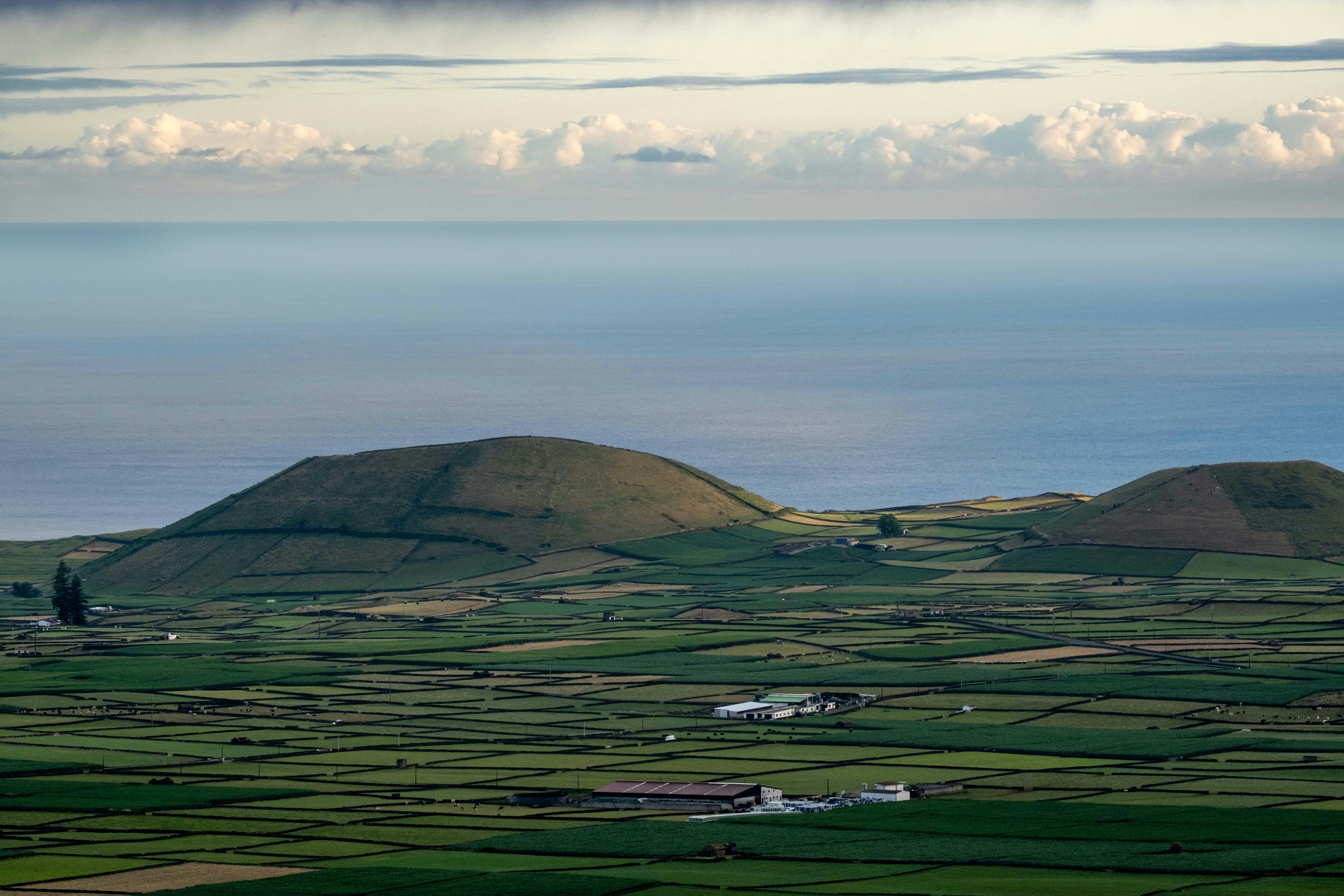 Green rolling hills with volcanic cones by the ocean