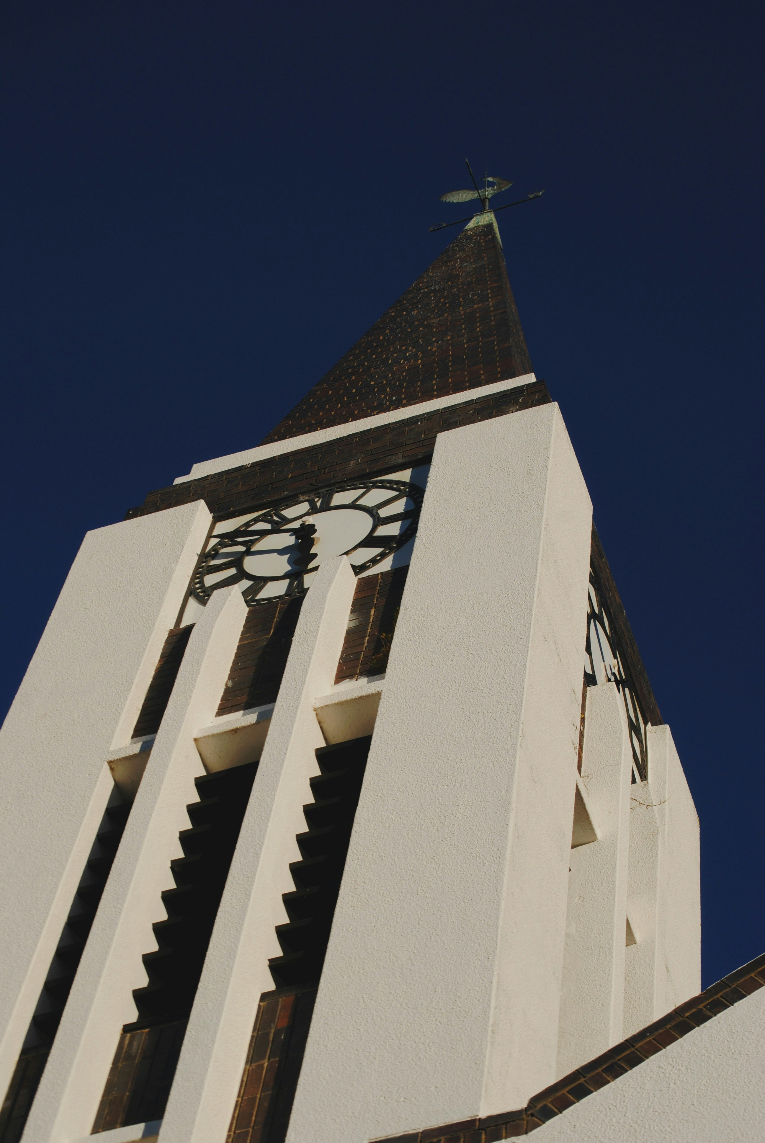 White church tower with clock against blue sky