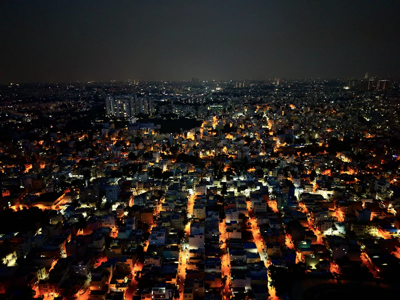 city lights spreading across dense rooftops at night, seen from above
