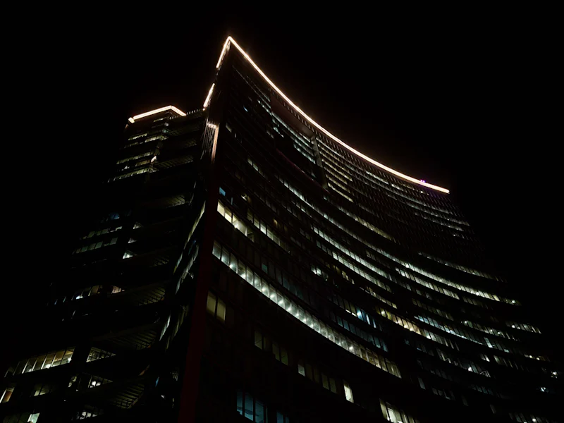 curved office tower edged with light against a black sky
