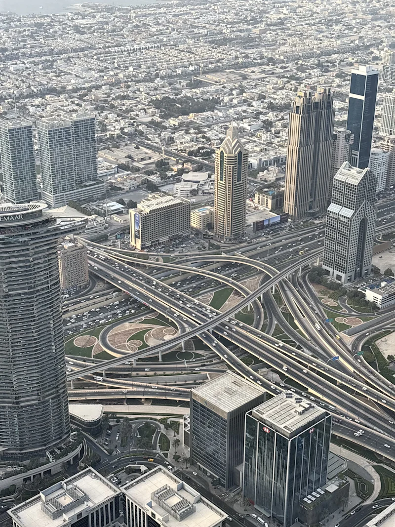 tangled highway interchange between glass towers, seen from high above