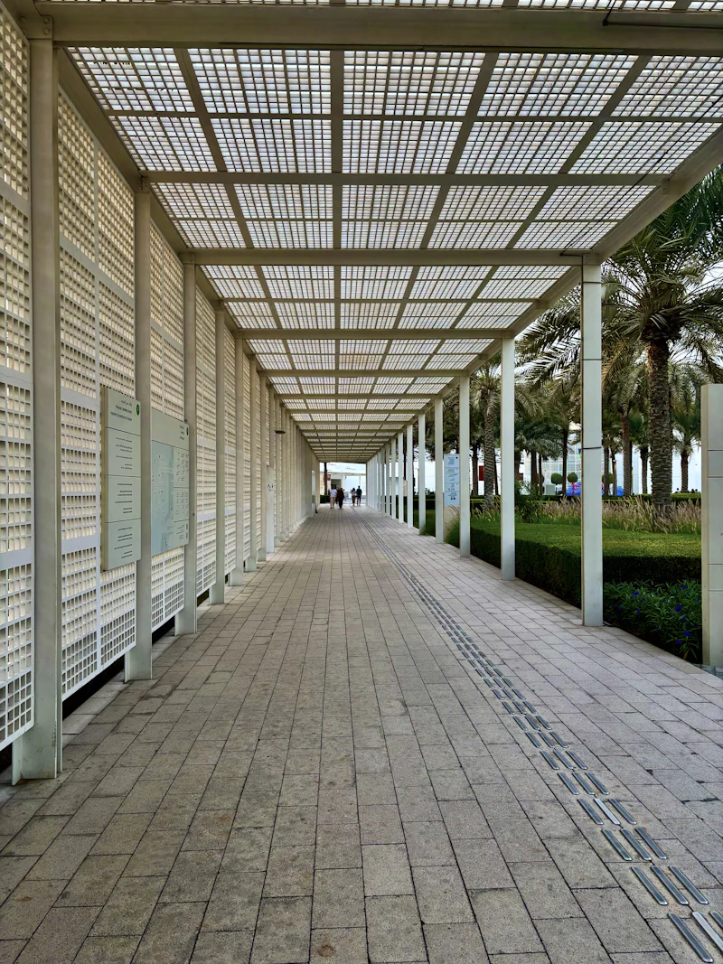 symmetrical walkway at the louvre abu dhabi featuring repeating columns and geometric roof pattern, creating a calm, minimalist architectural perspective