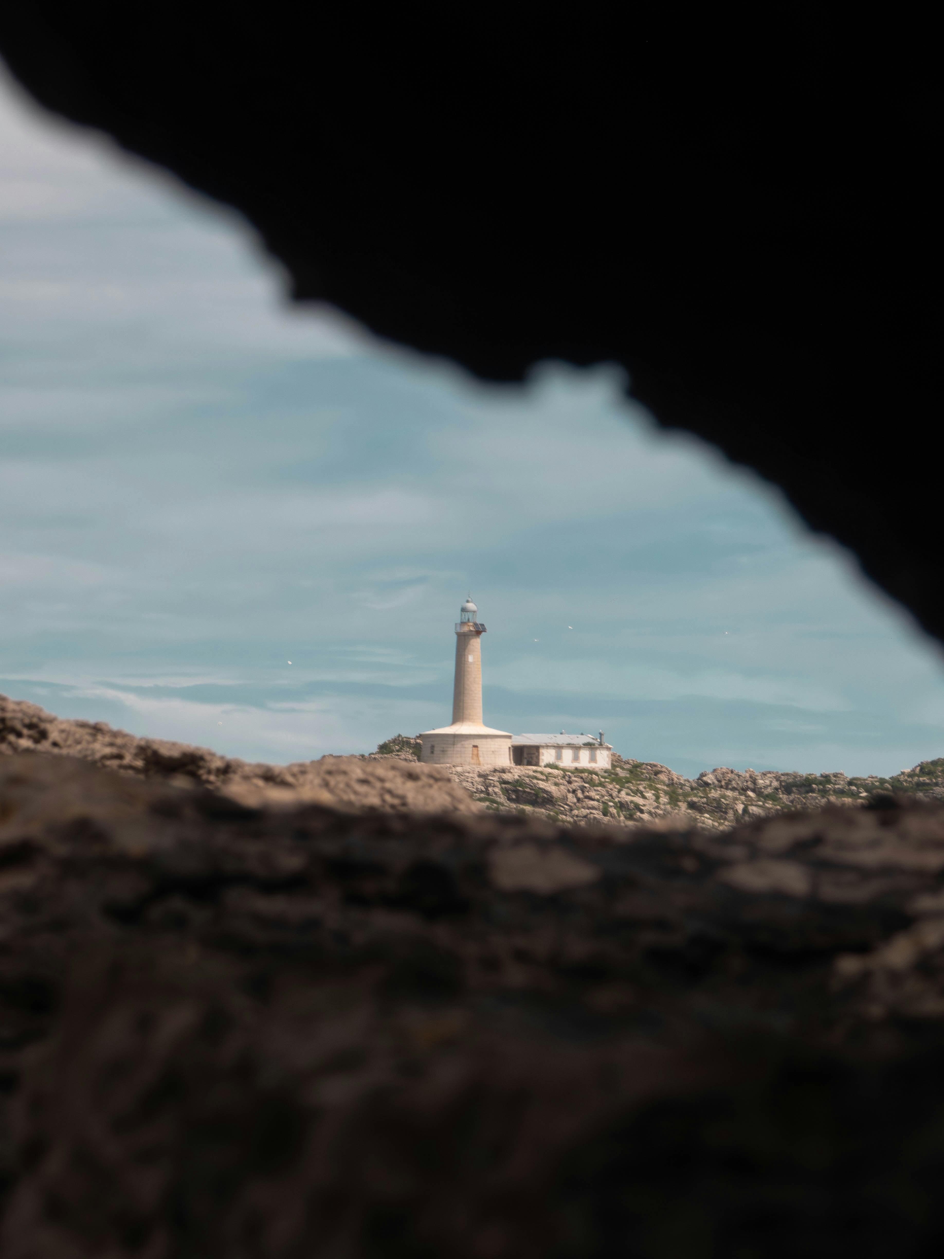Lighthouse on a rocky hill under a cloudy sky
