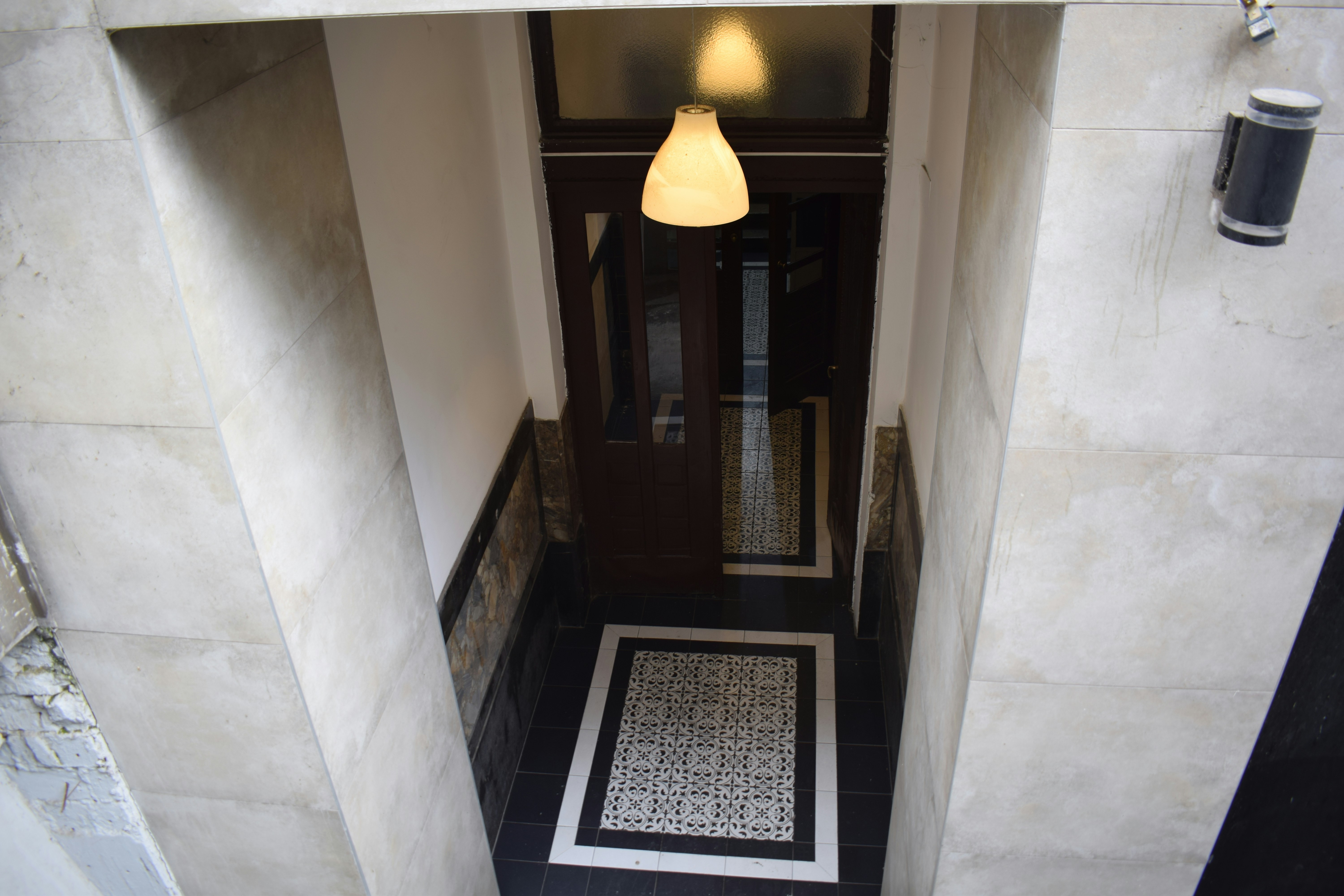 Interior hallway with patterned floor tiles and lamp.