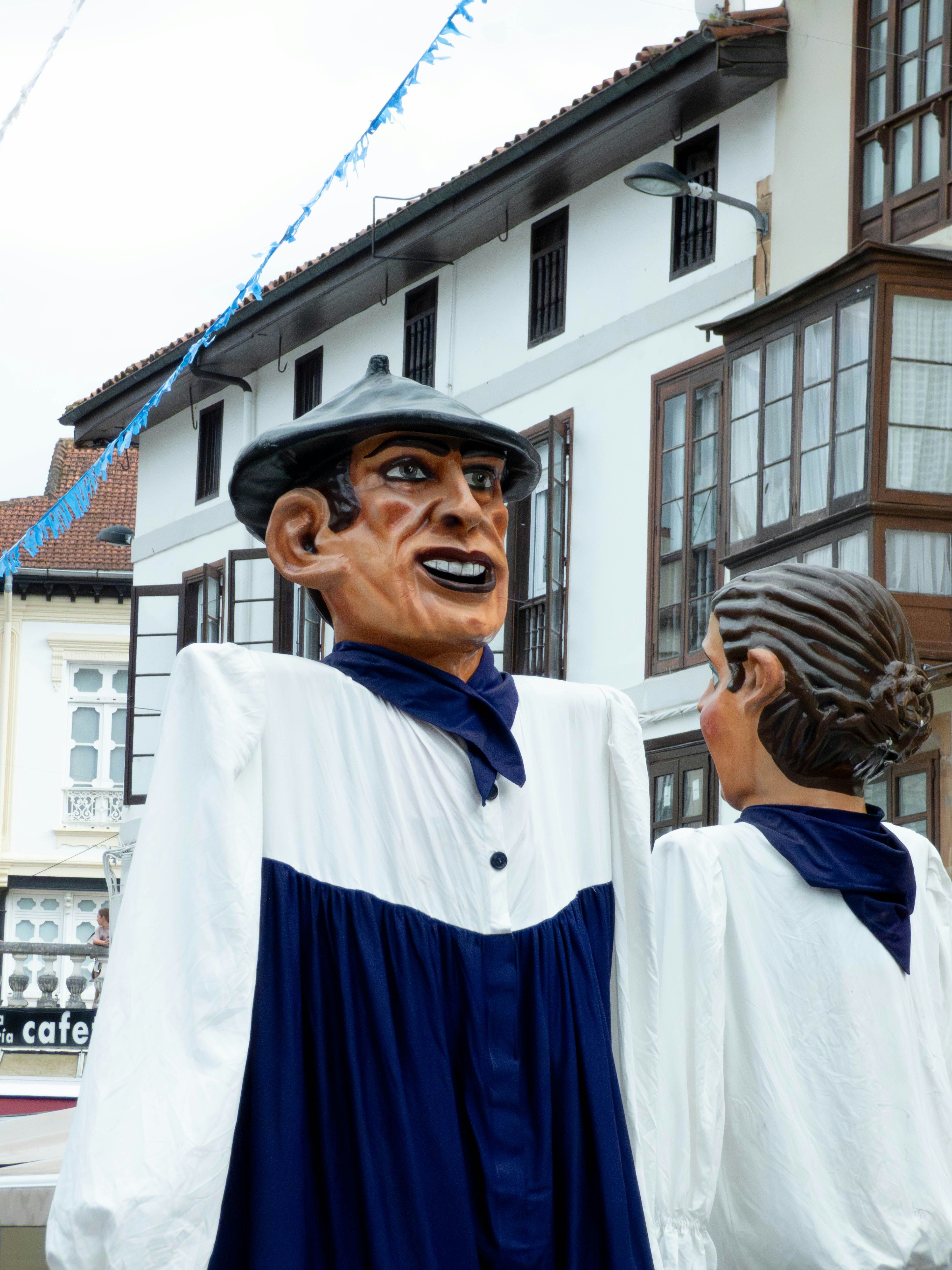Two giant figures in traditional clothing stand outdoors.