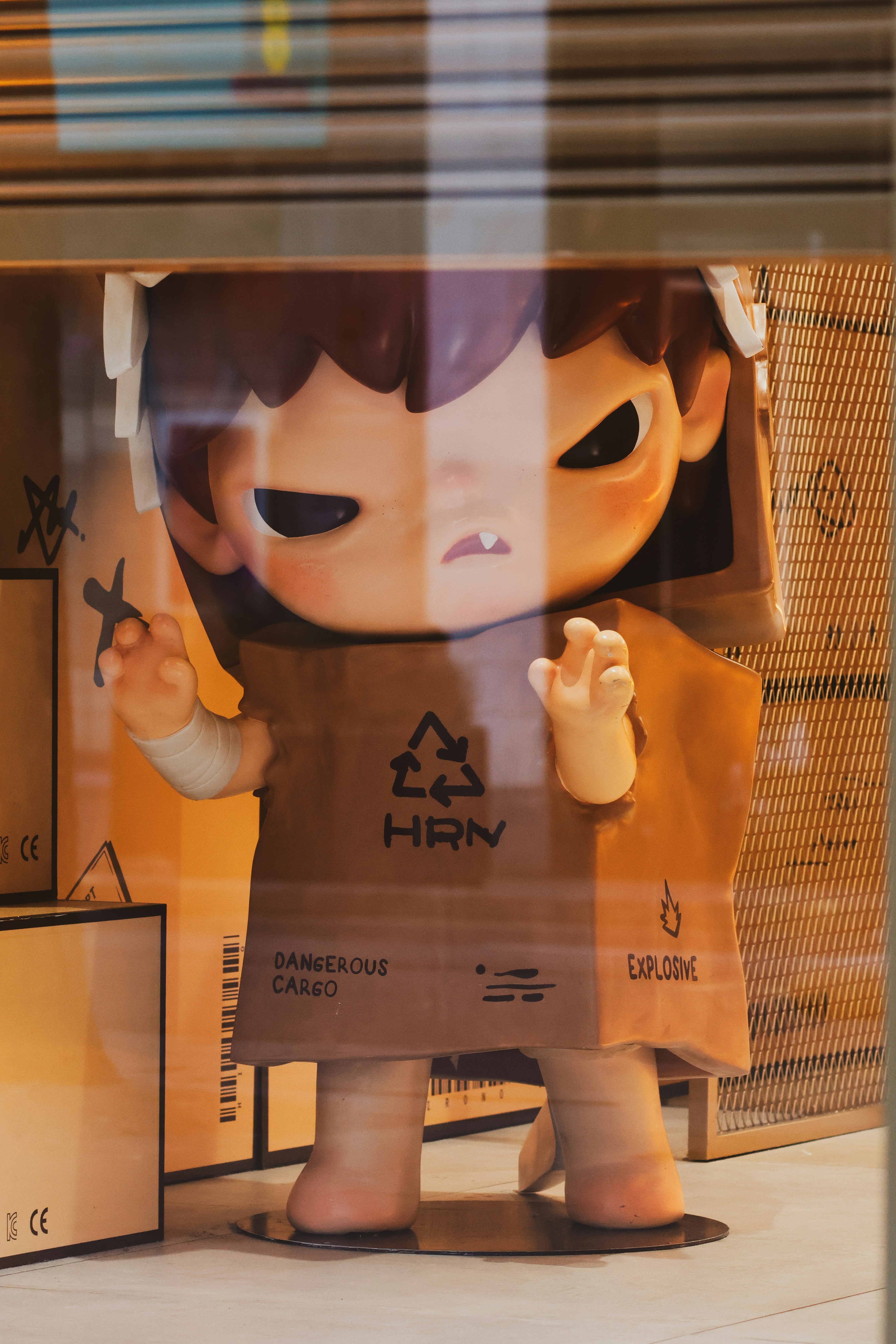 A doll peeking out from a cardboard box.