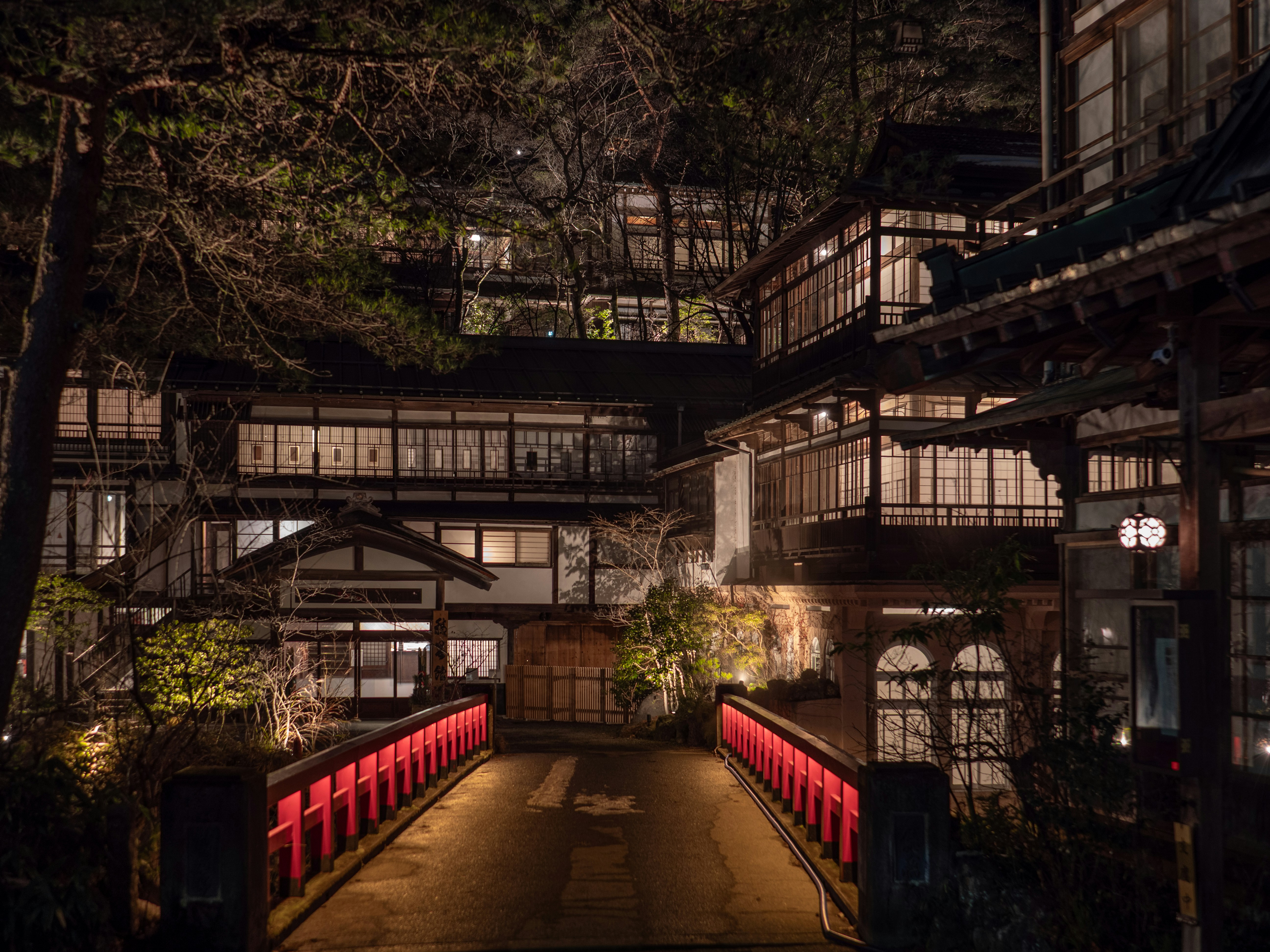 Traditional japanese inn illuminated at night with red bridge.