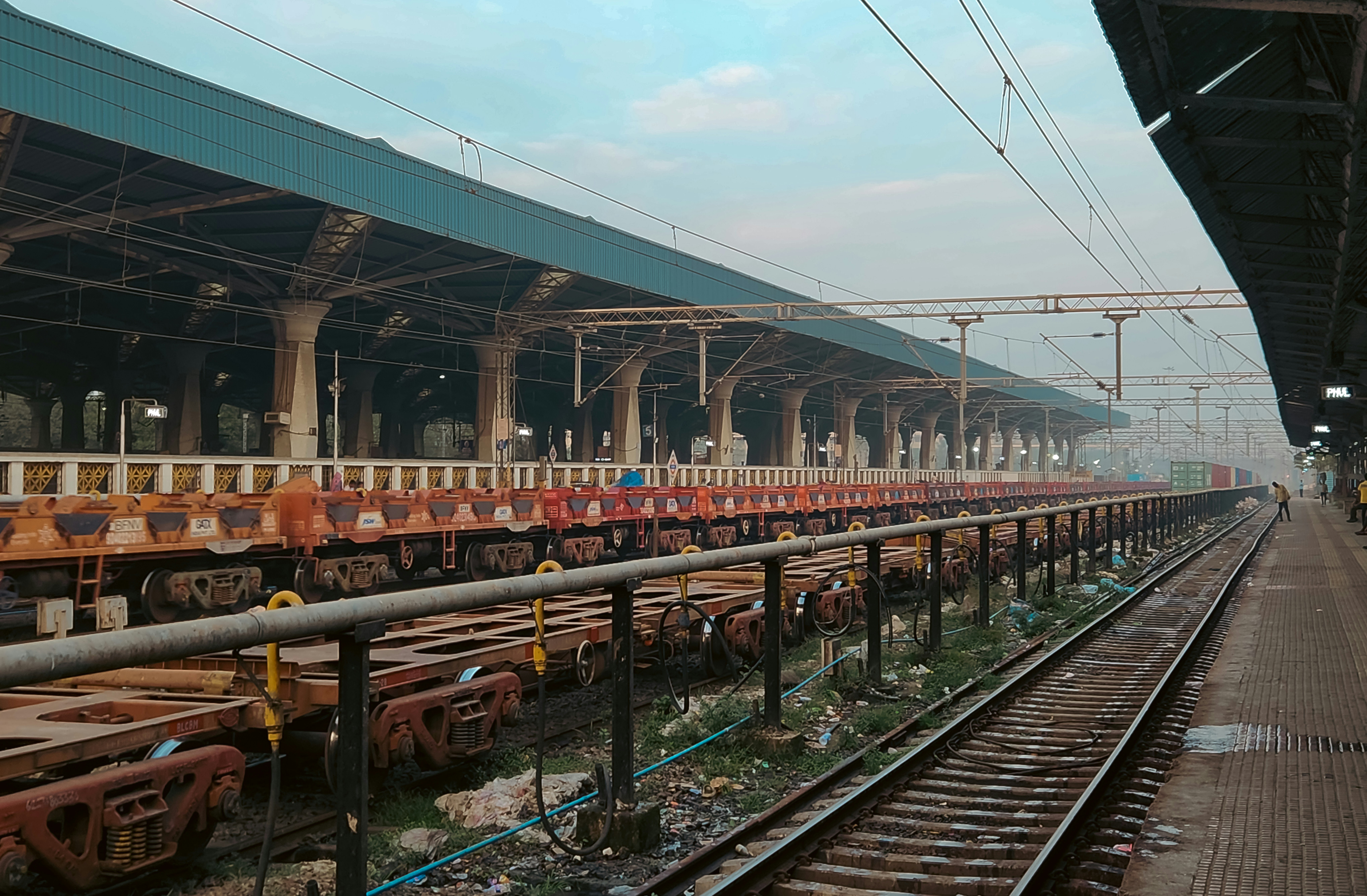 An aerial view of a busy Indian railway station with multiple platforms, showing dense train traffic and passenger movement.