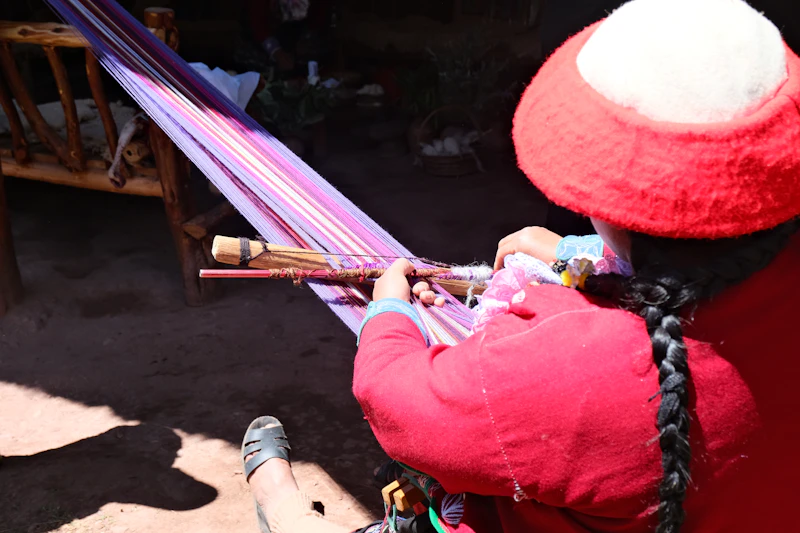 An Andean woman weaving colourful cloth on a backstrap loom near Chinchero