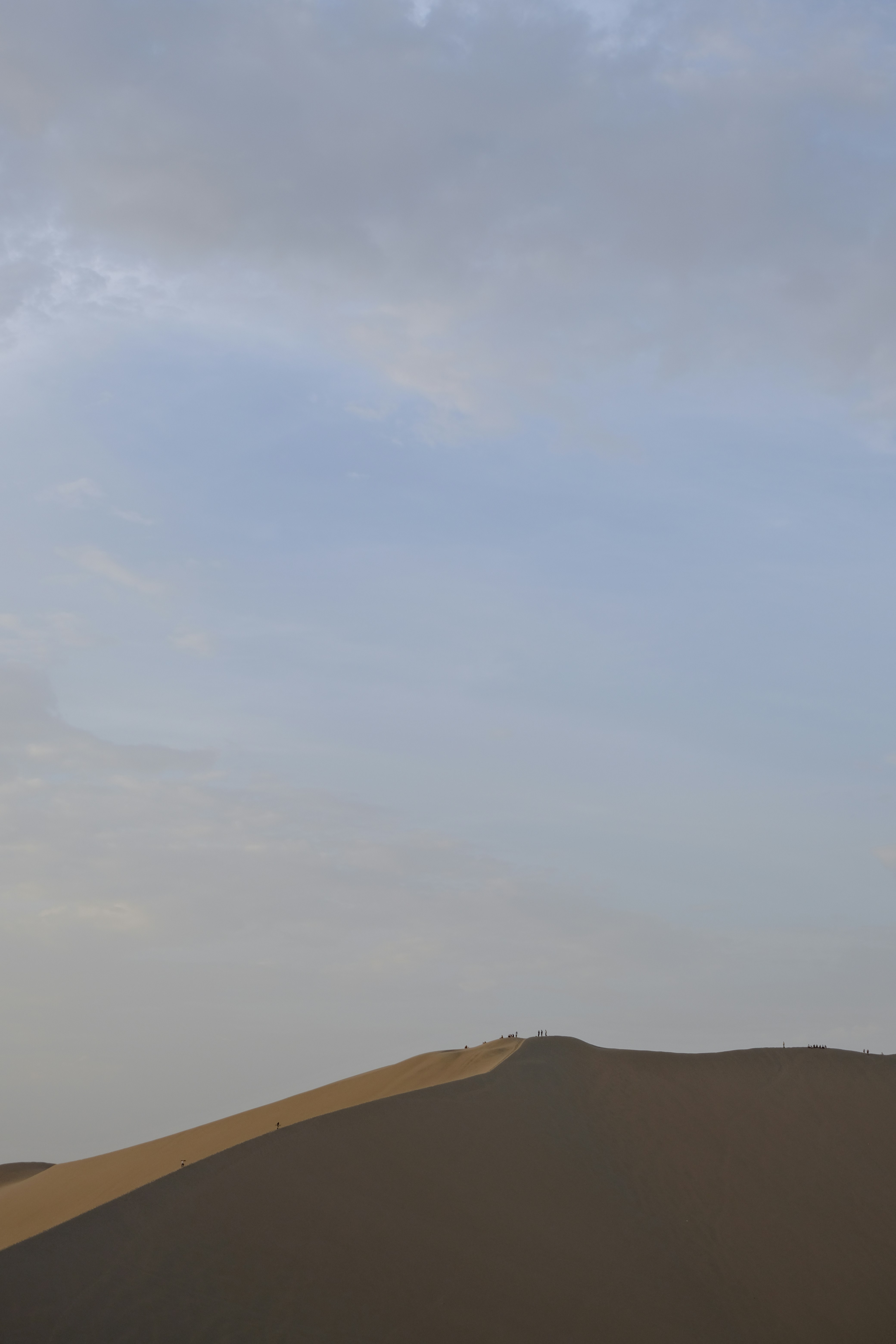 A vast sand dune under a cloudy sky