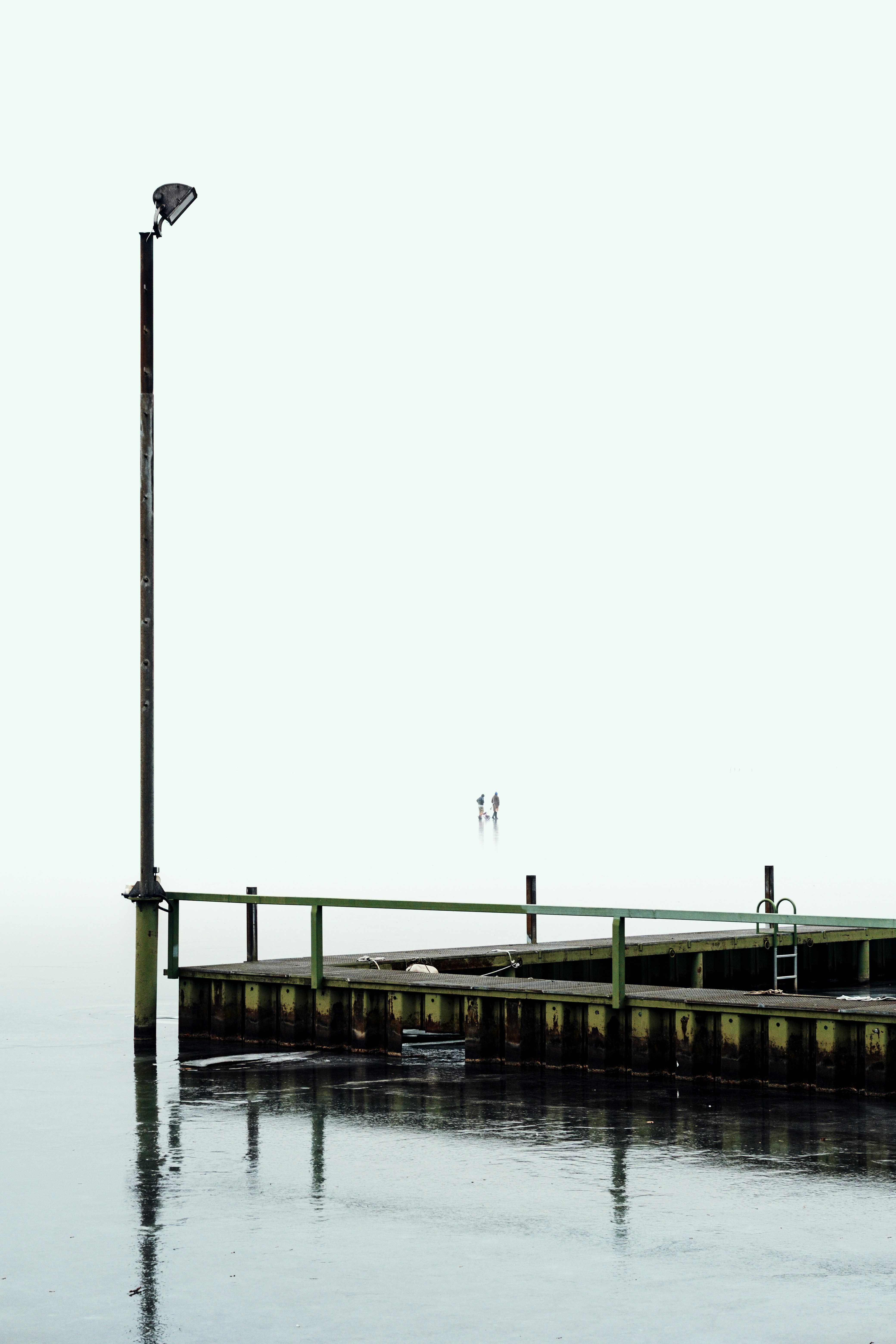 A wooden pier with a lamppost on a foggy day