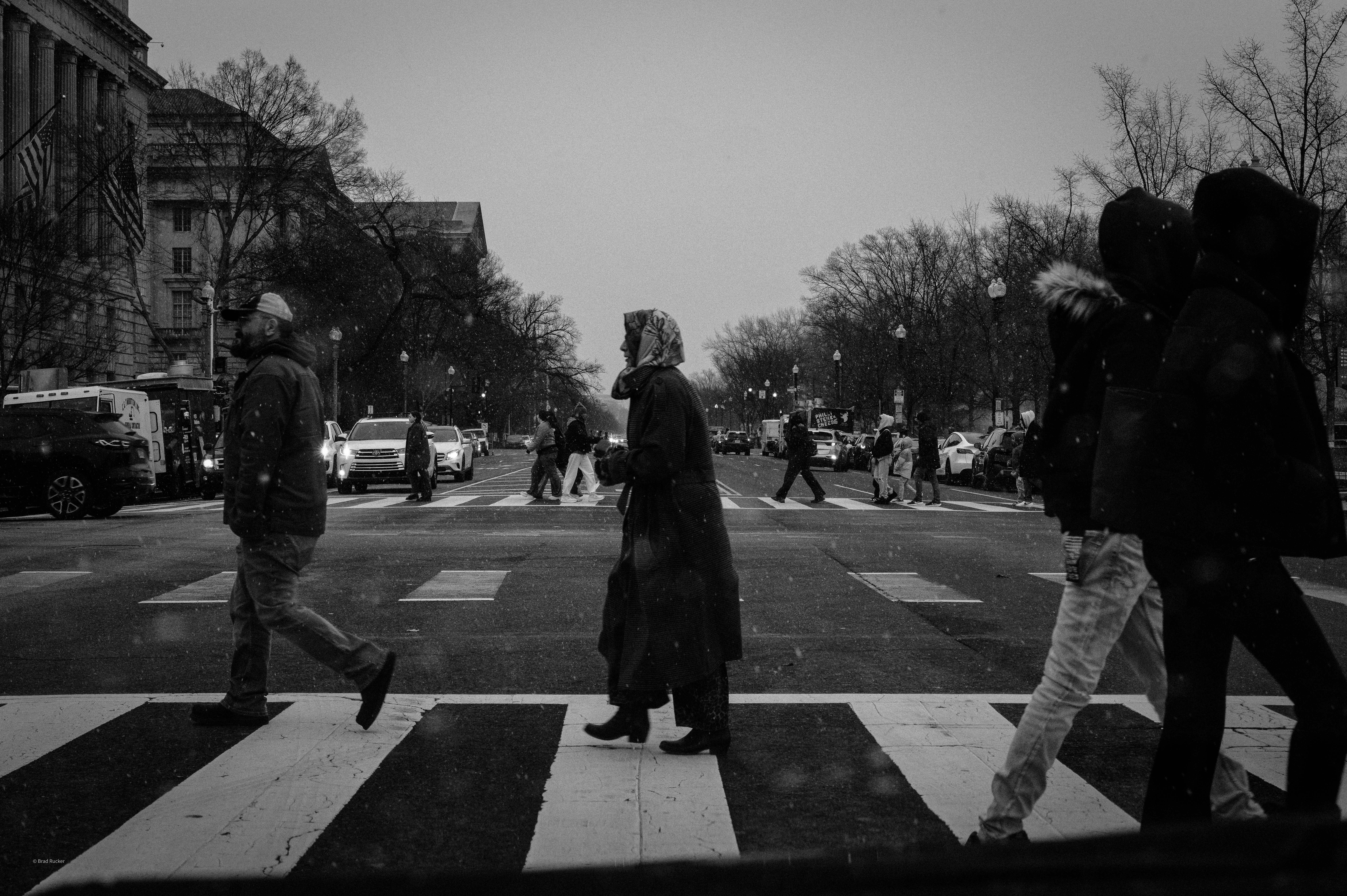 People crossing a street at a crosswalk in winter.