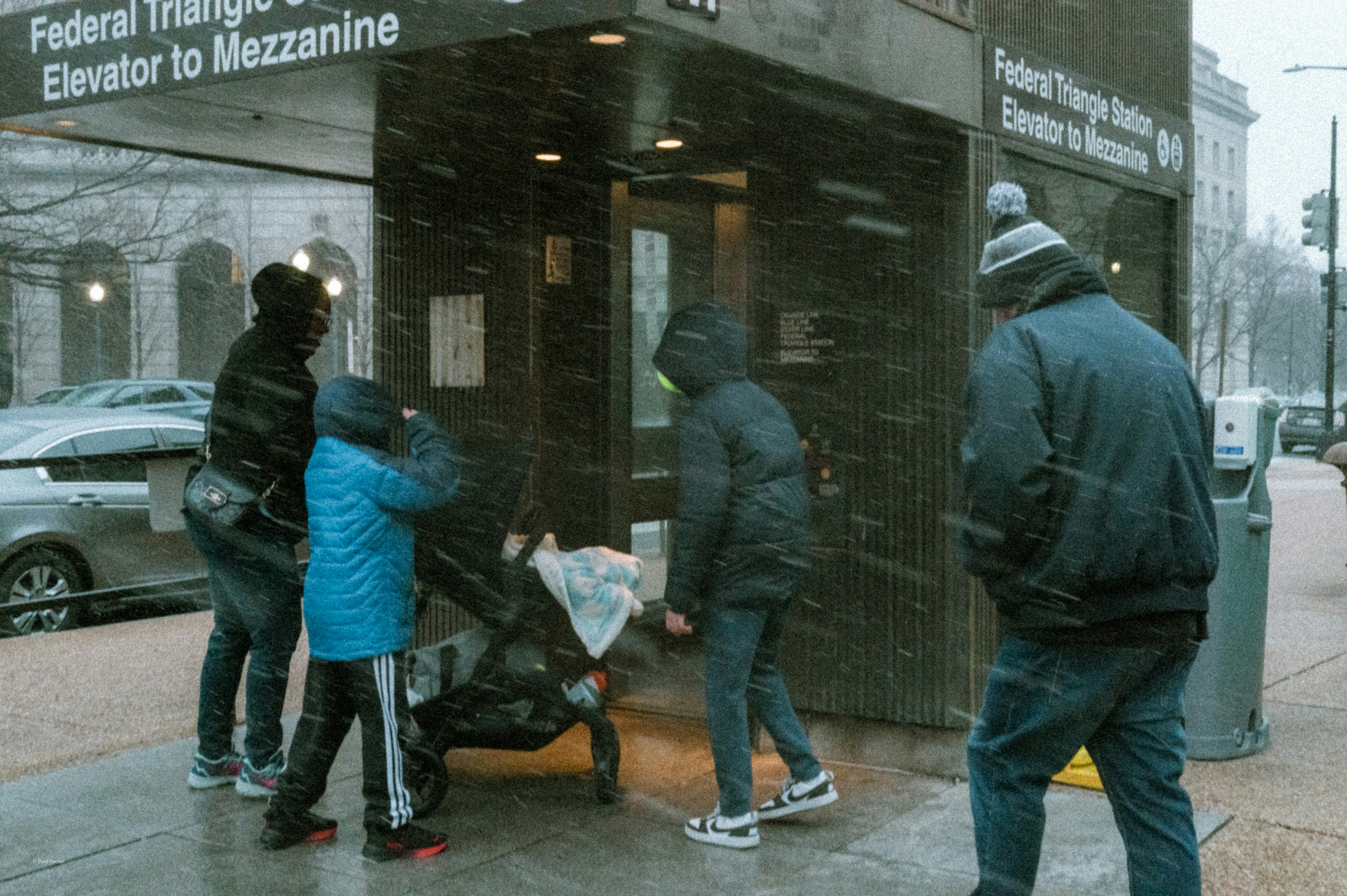 People gather near an elevator entrance during snowfall.
