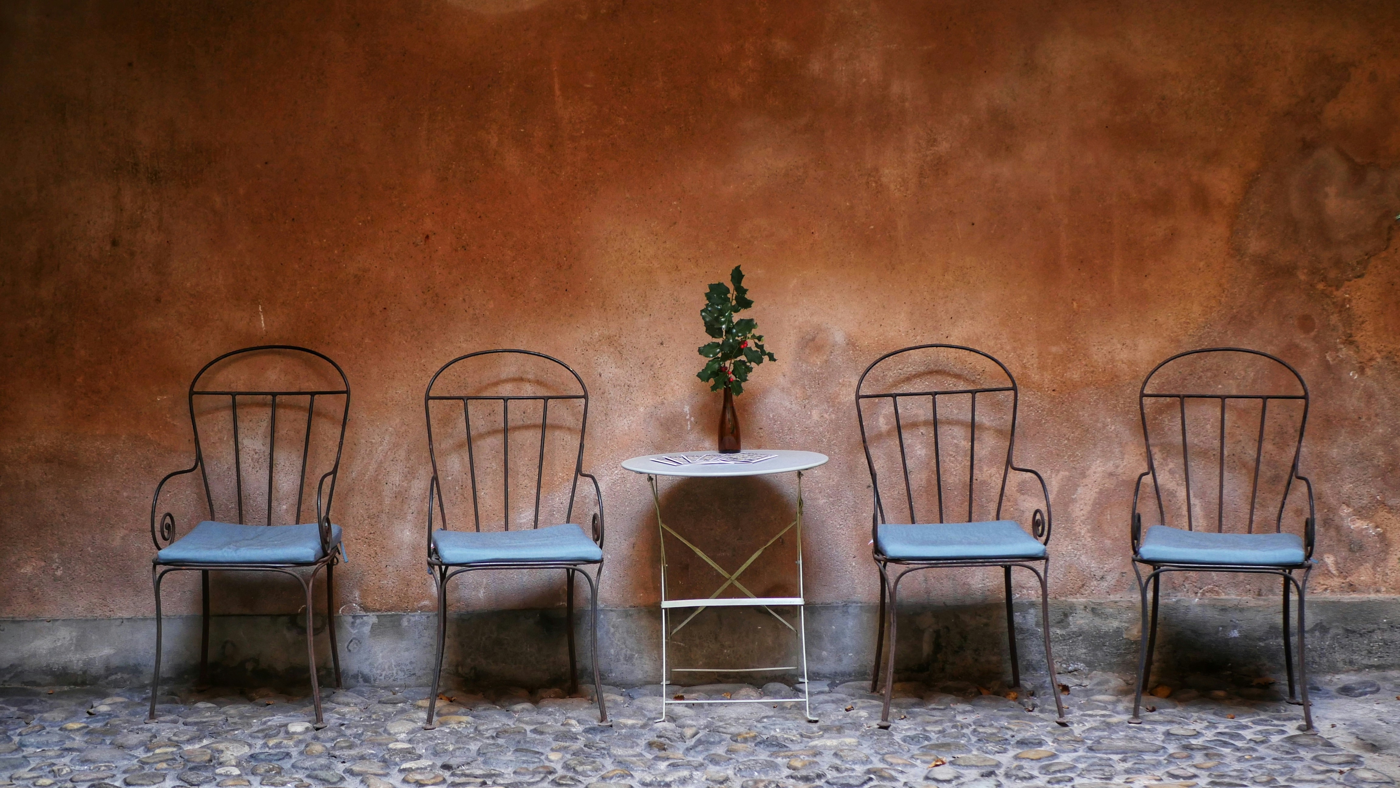 四脚の椅子と、テクスチャーのある壁に立てかけられたテーブル