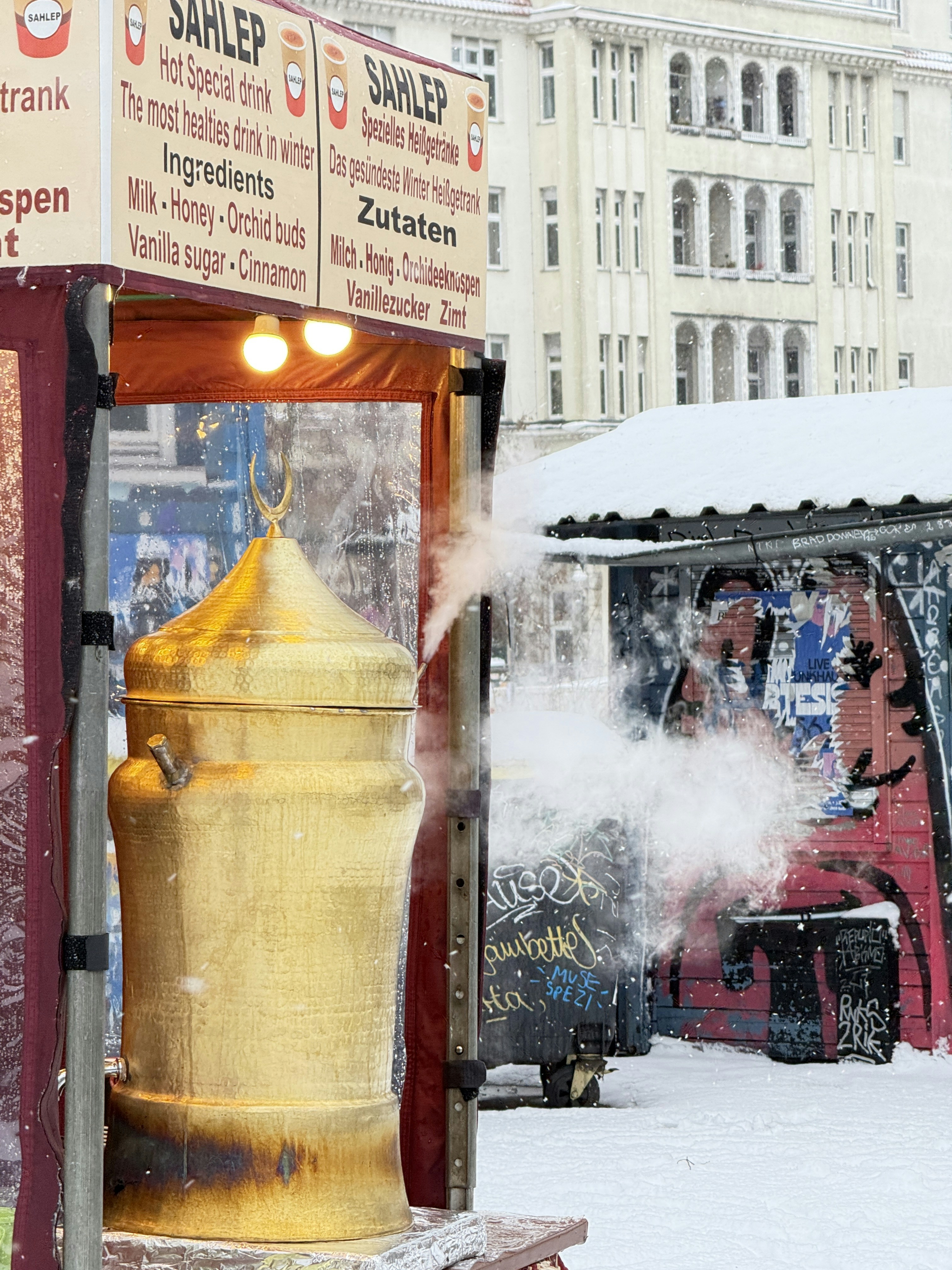 A golden urn steaming in a snowy outdoor market.