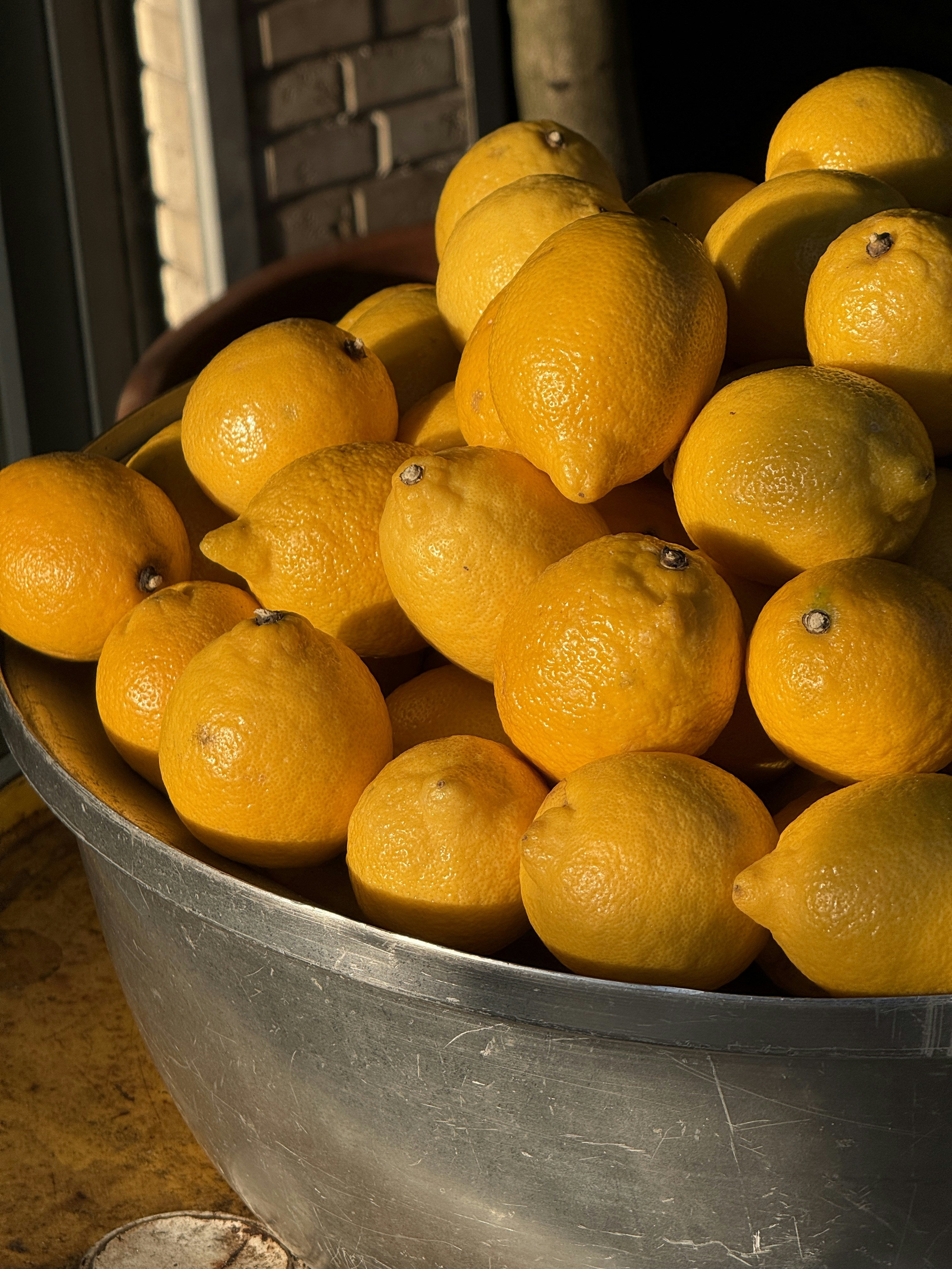 A large bowl filled with fresh, ripe lemons.
