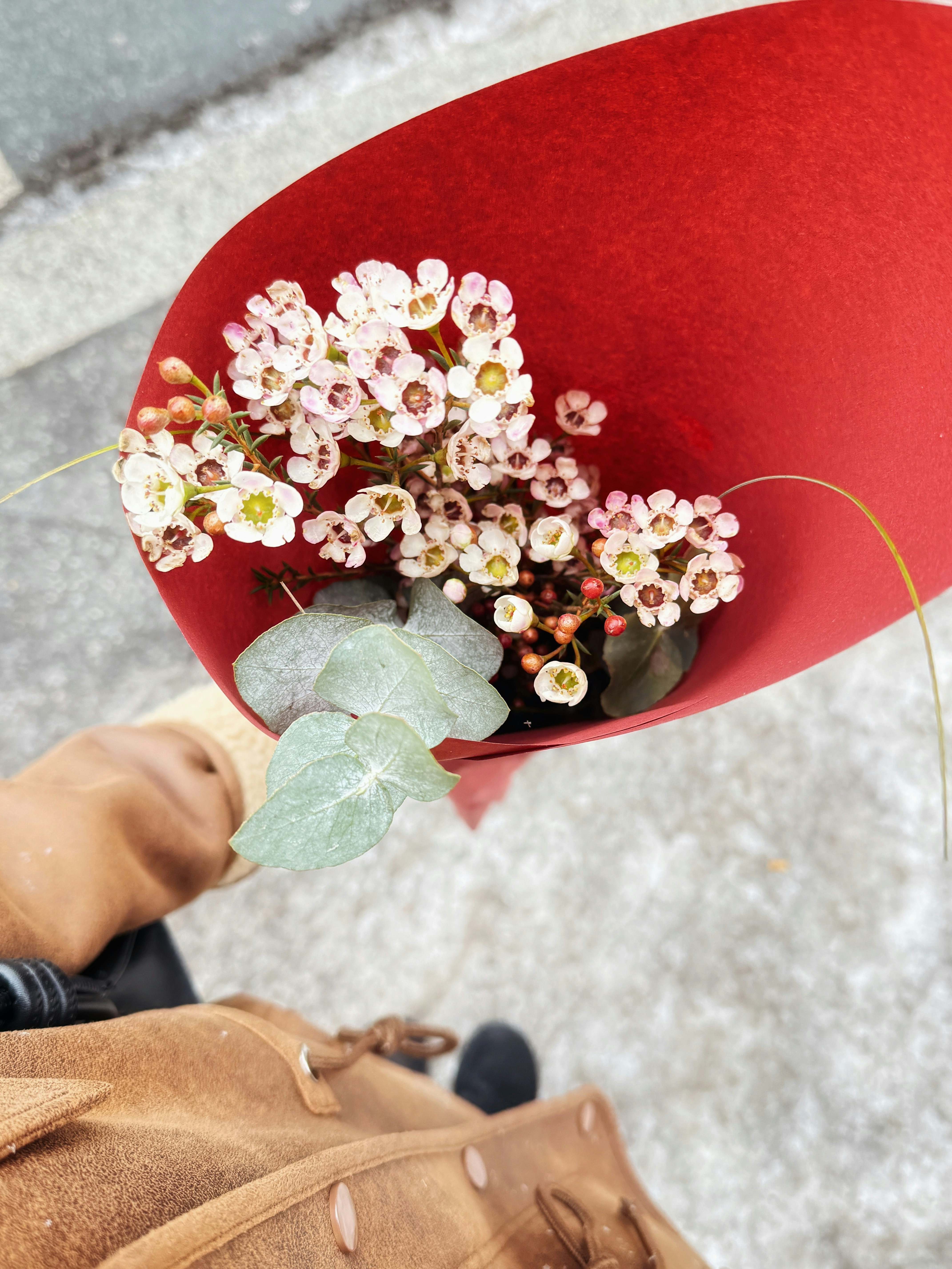 A bouquet of small white flowers in red paper.