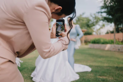 Woman in pink suit photographs bride in light blue dress.