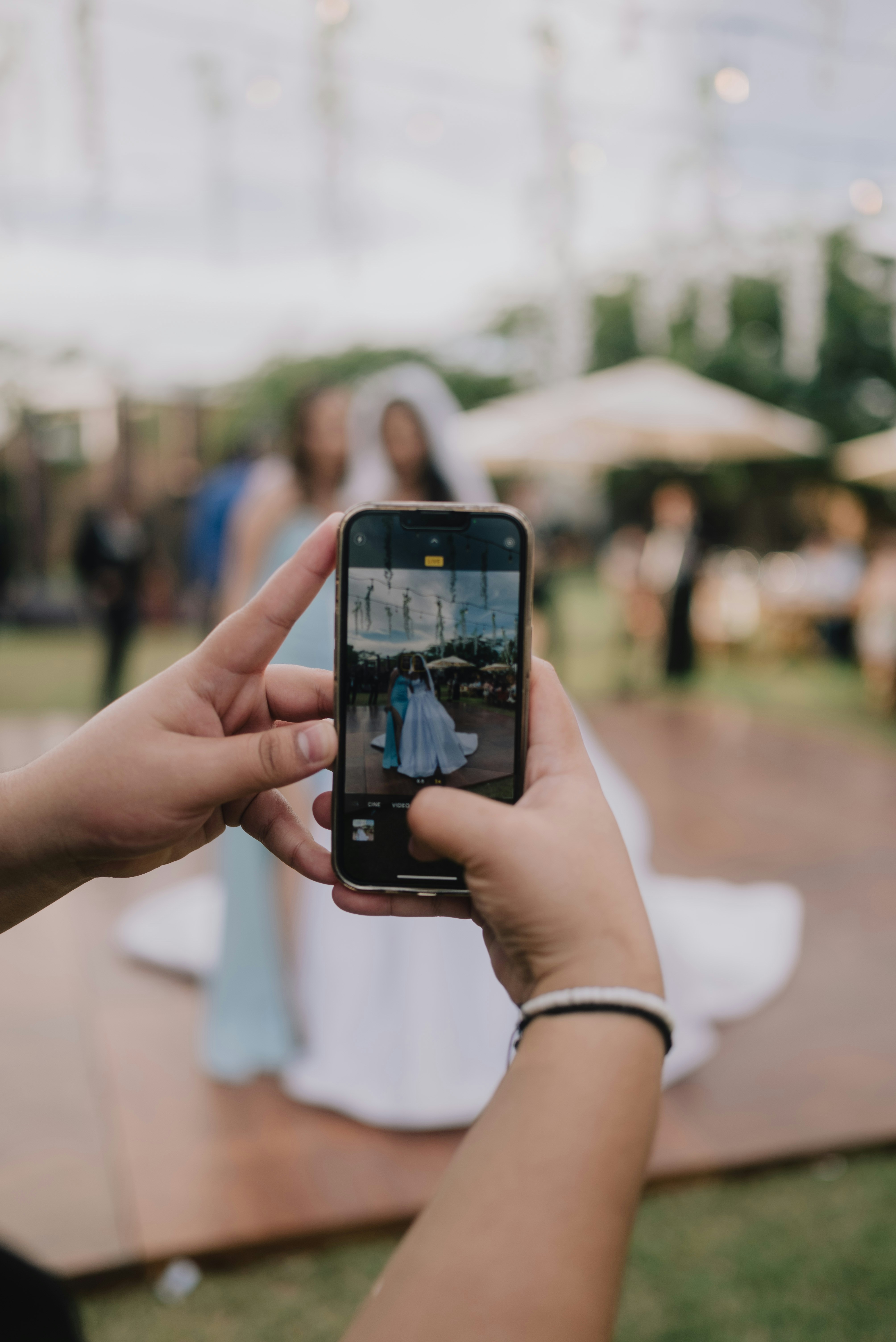 Hands holding phone taking picture of bride