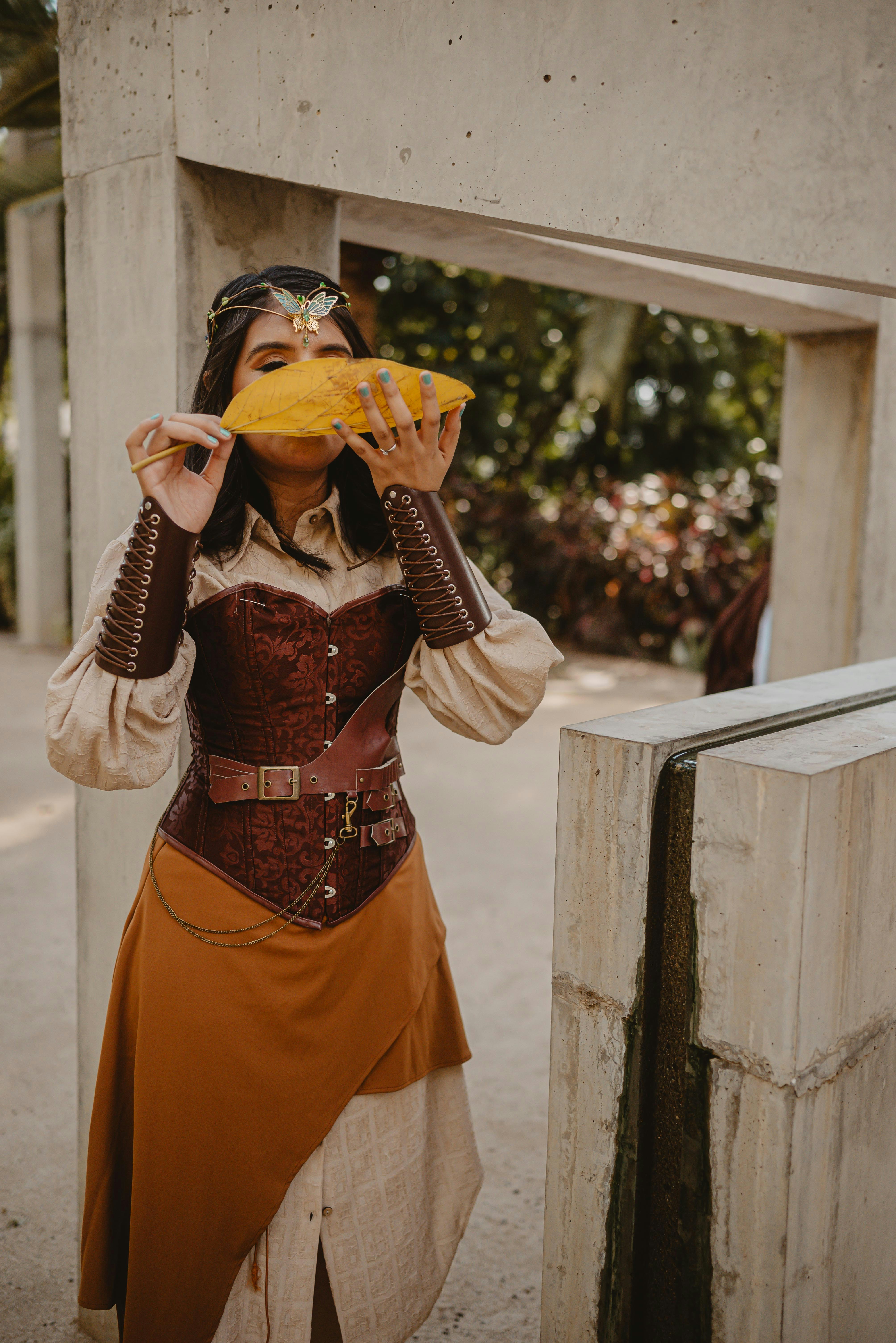 Wanita berpakaian steampunk makan sepotong buah besar.