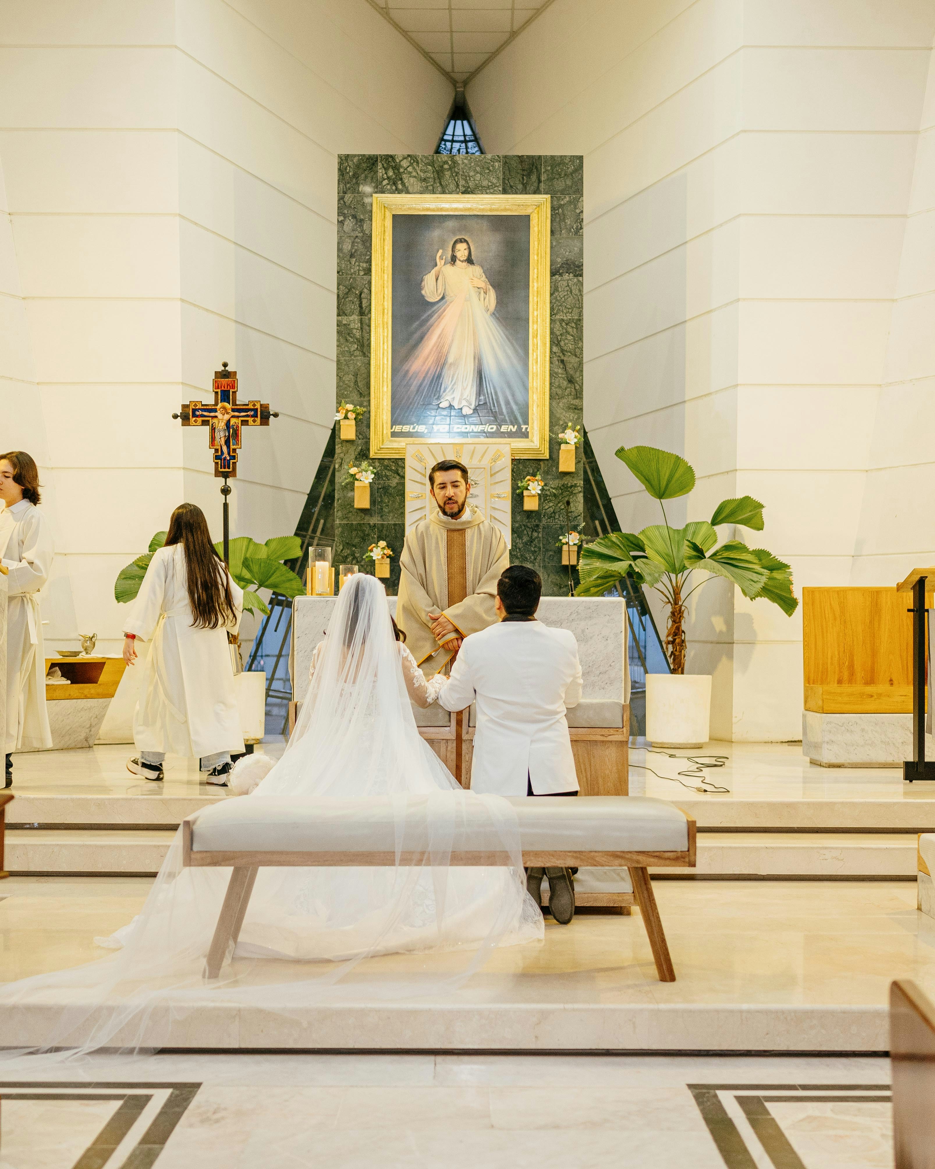 Pareja arrodillada ante el sacerdote durante la ceremonia de boda