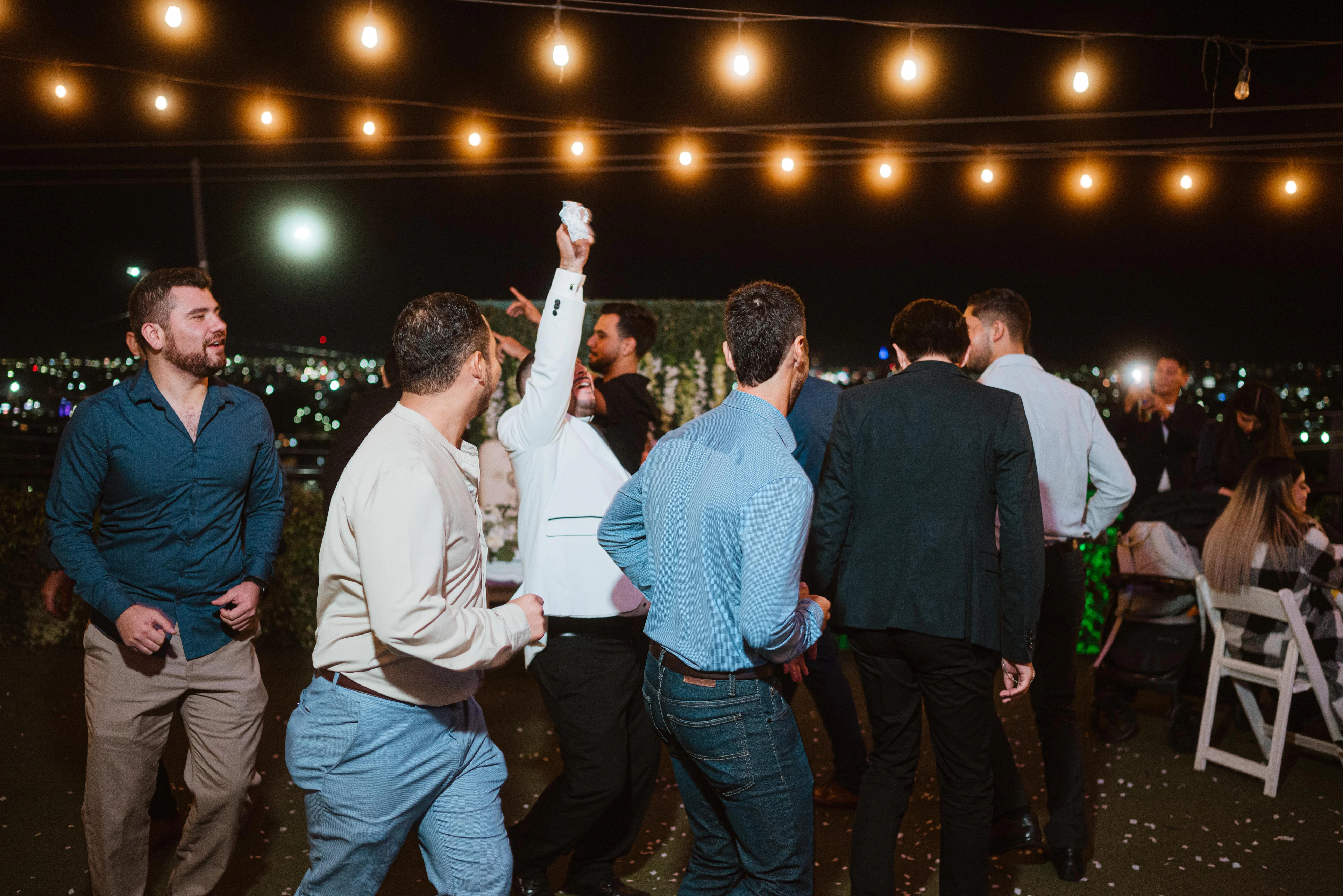 Friends dancing under strings of lights at a night-time party