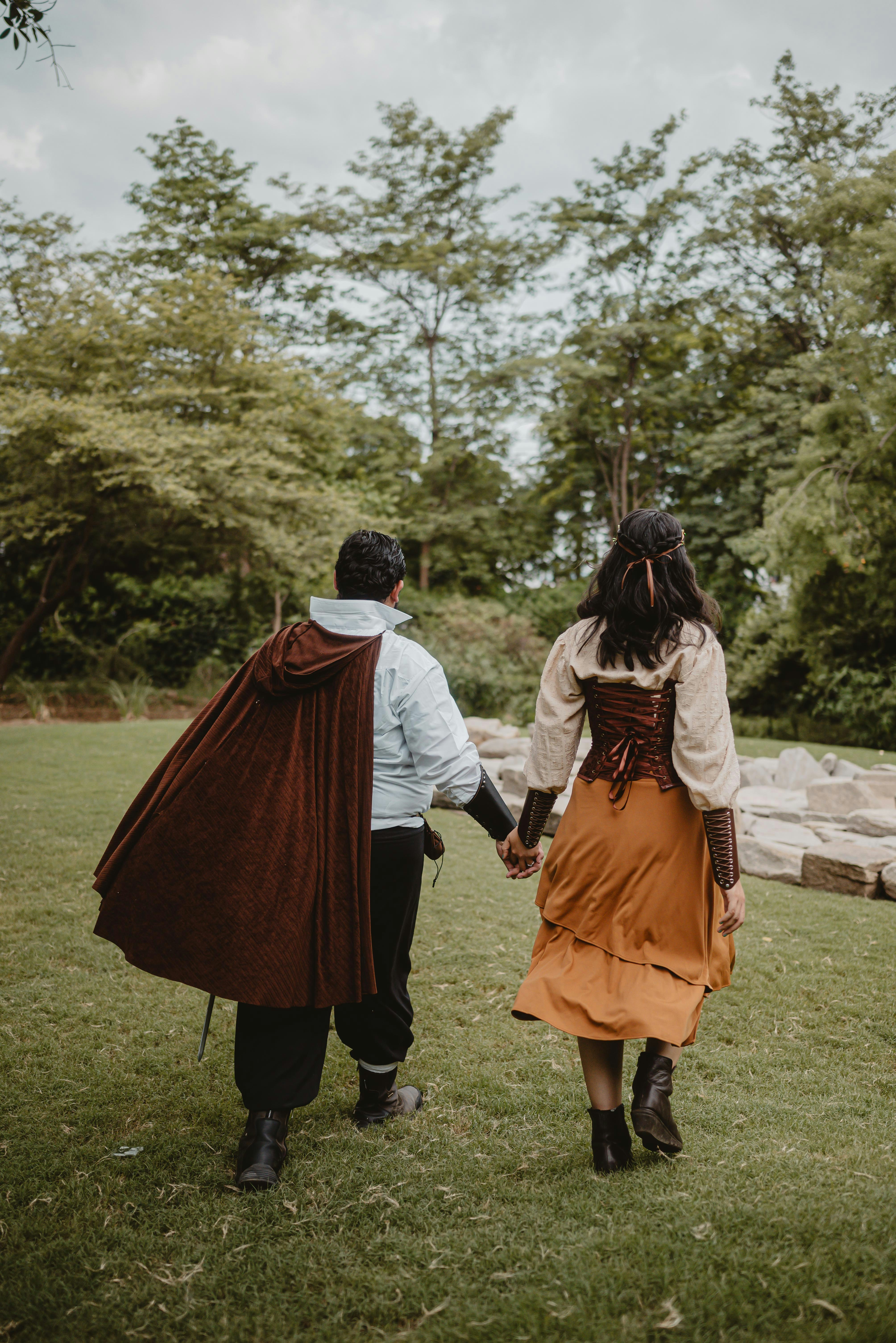 Pareja con disfraces de fantasía paseando por un parque de césped