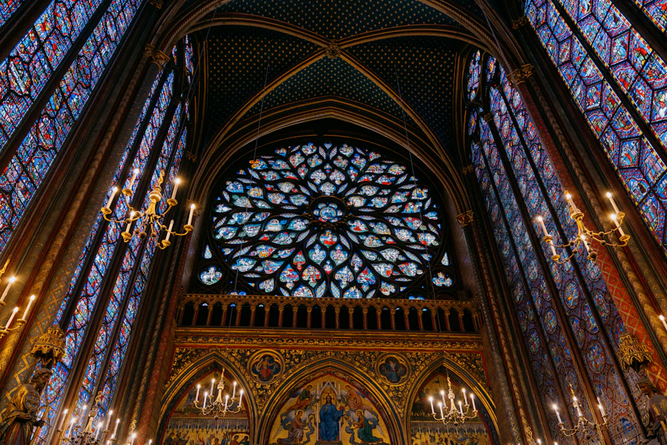 Large stained glass window dominates grand cathedral interior with intricate designs and vibrant colors